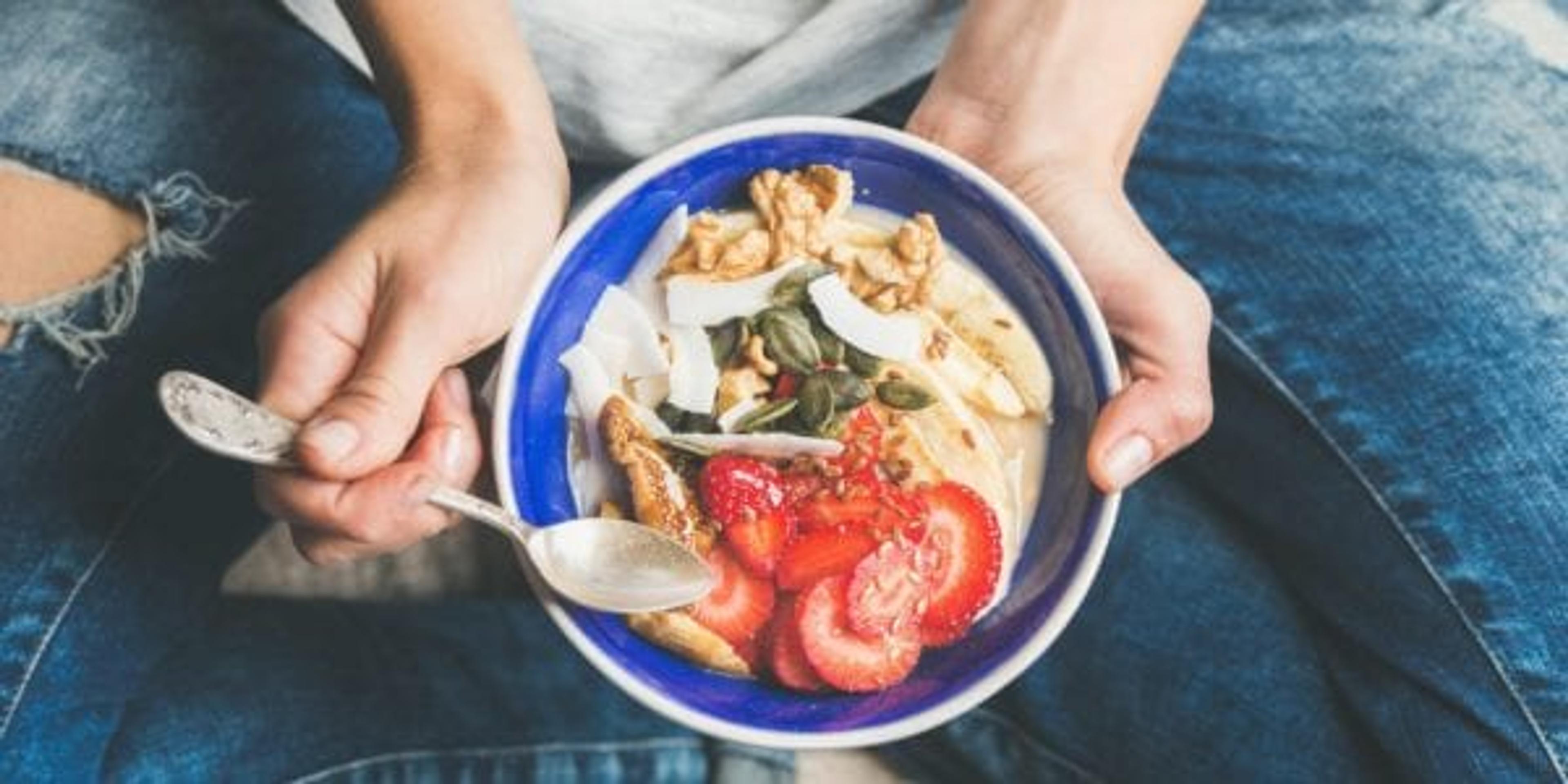 Woman sitting cross-legged with plate of healthy food in lap