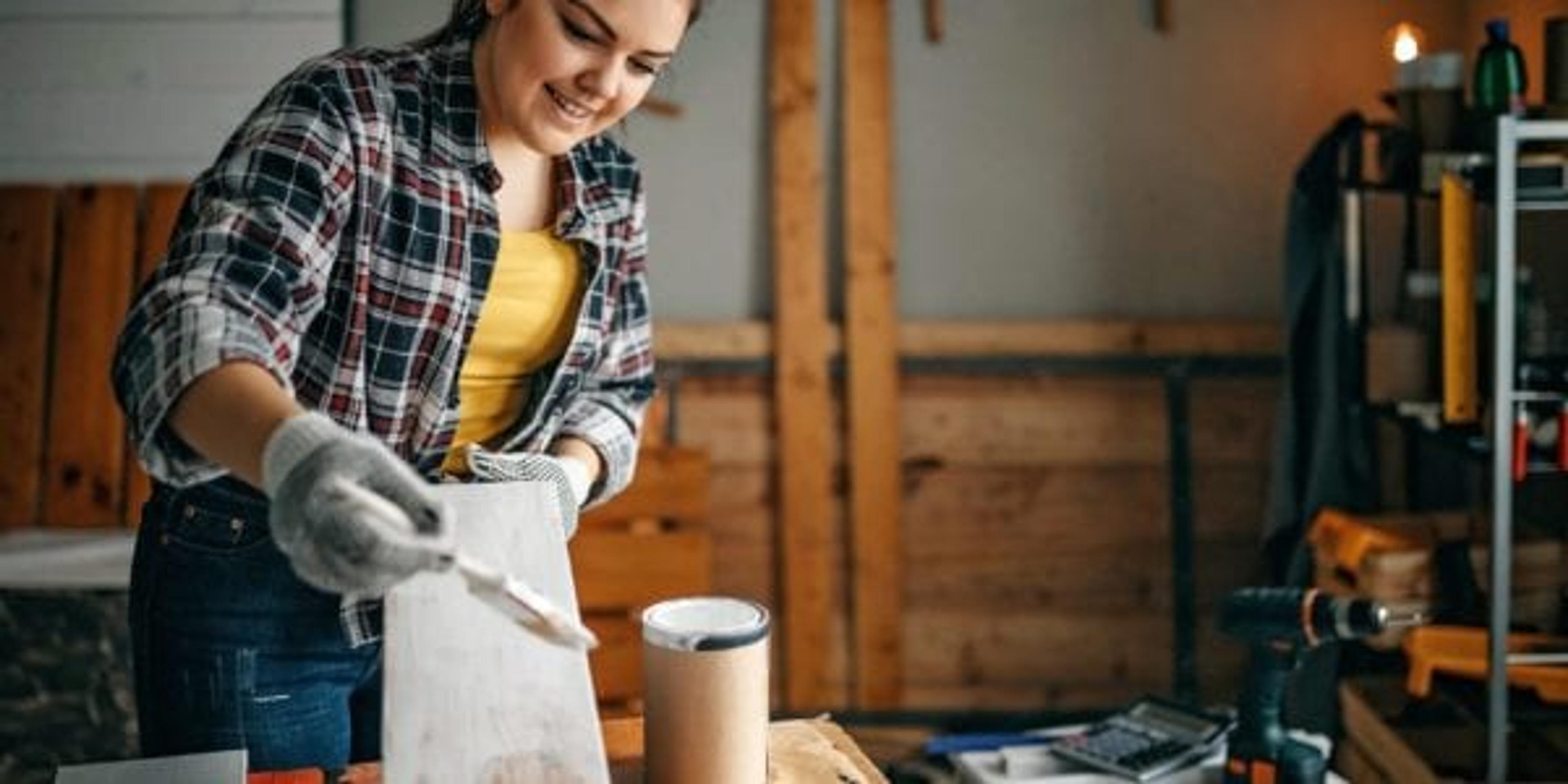 Woman painting plank in garage