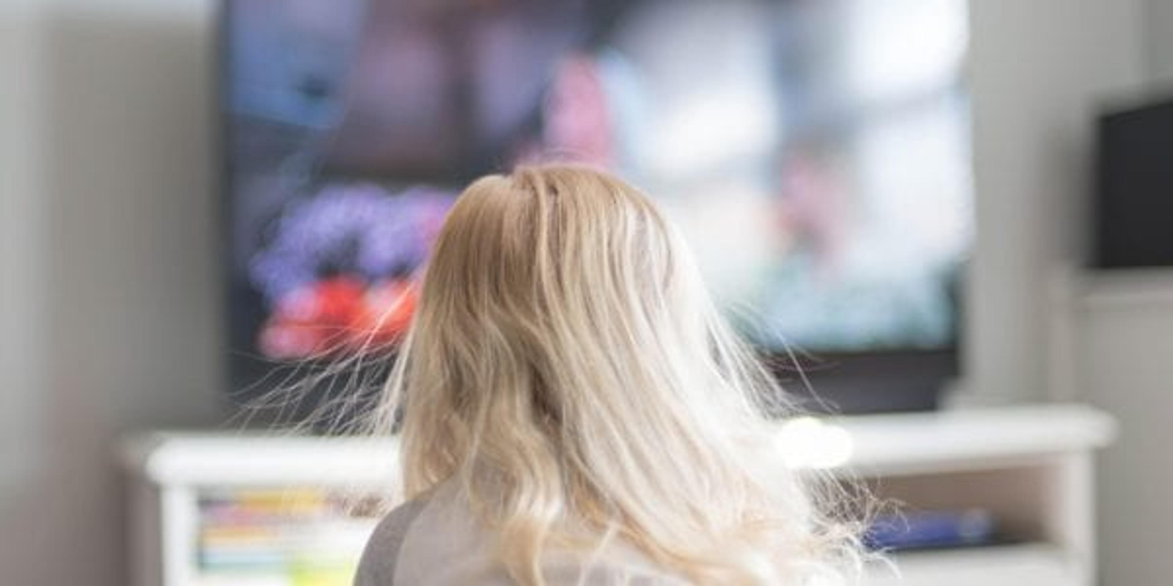 Young girl with blonde hair with static electricity watching TV