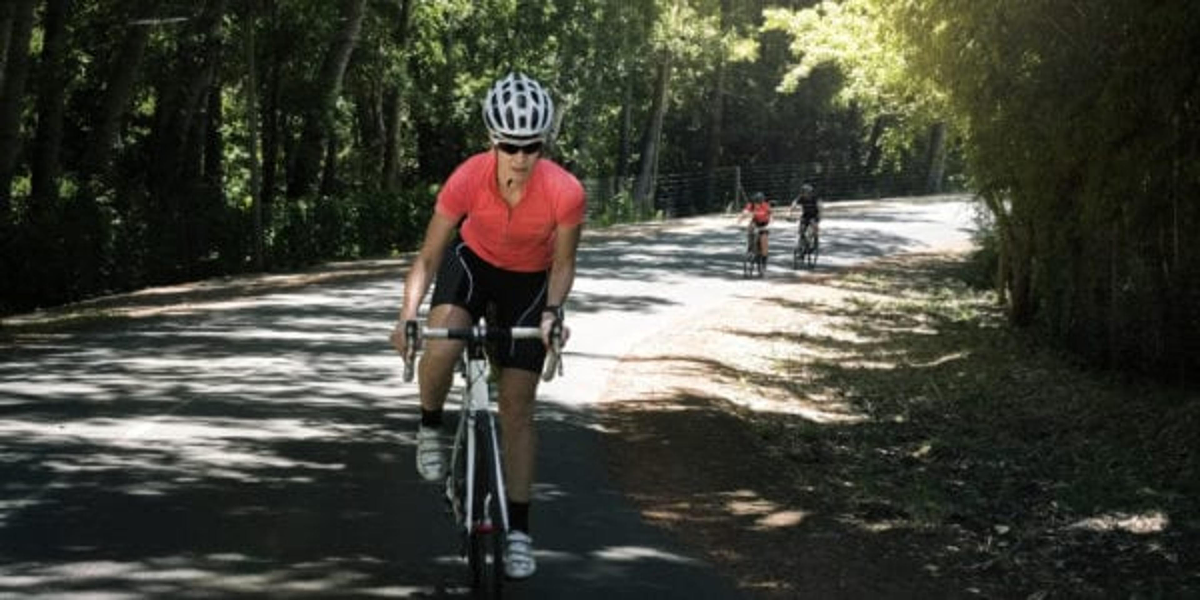 Female cyclist wearing neon colors riding on a bike path