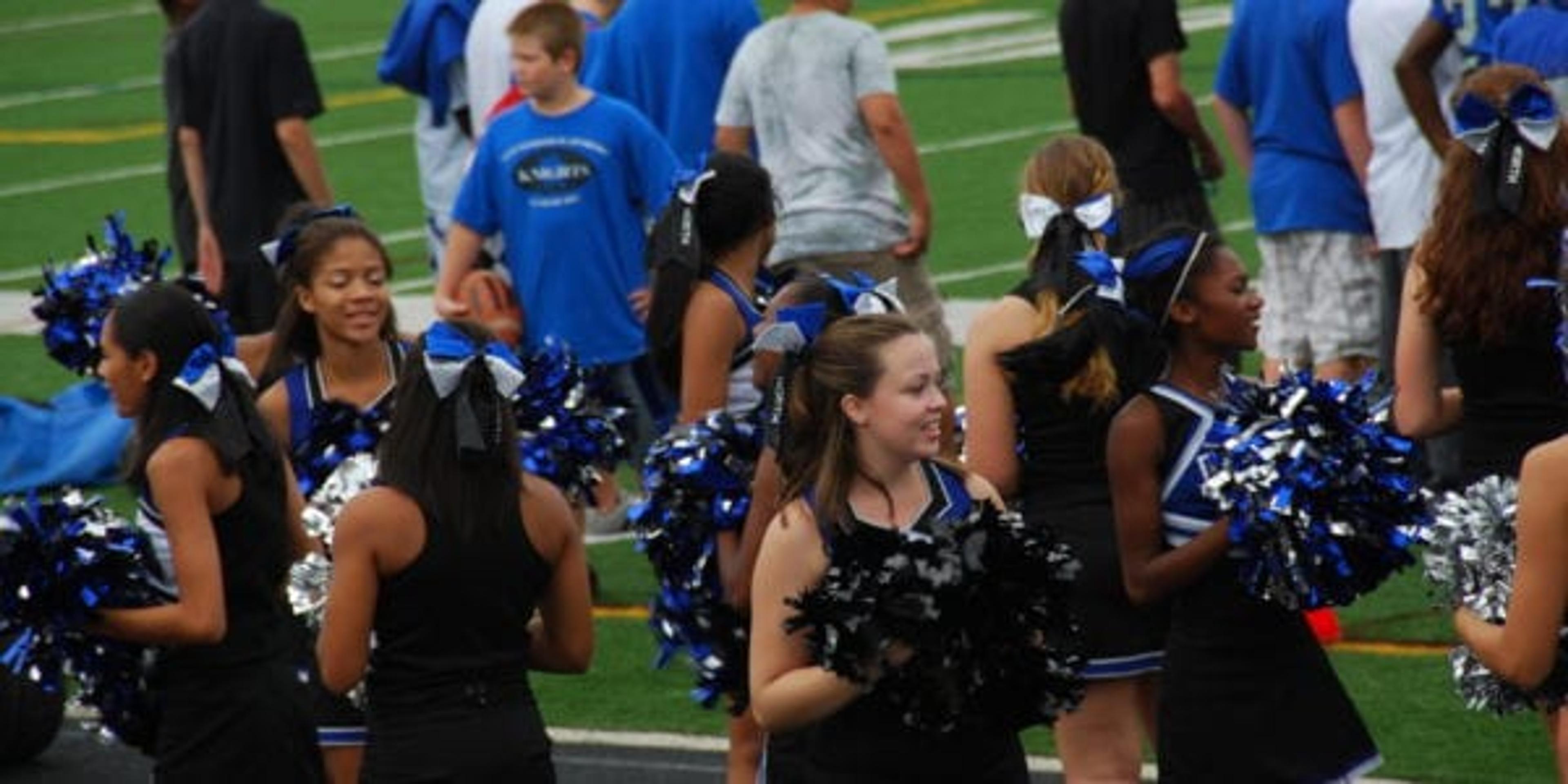 Cheerleaders near track at a football game