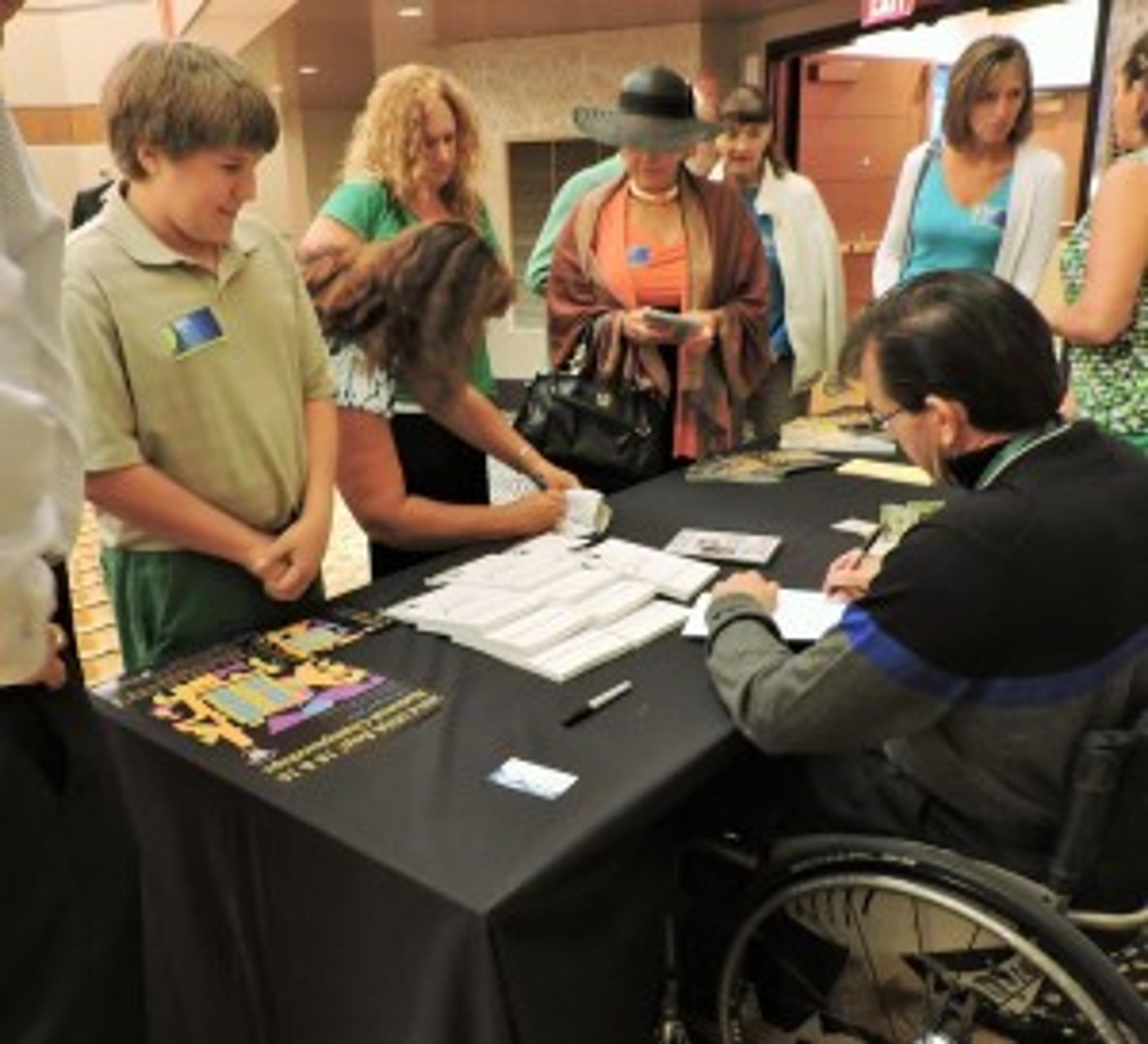 Mike Schlappi signs a book for Will Scott, 15, of Plainwell.