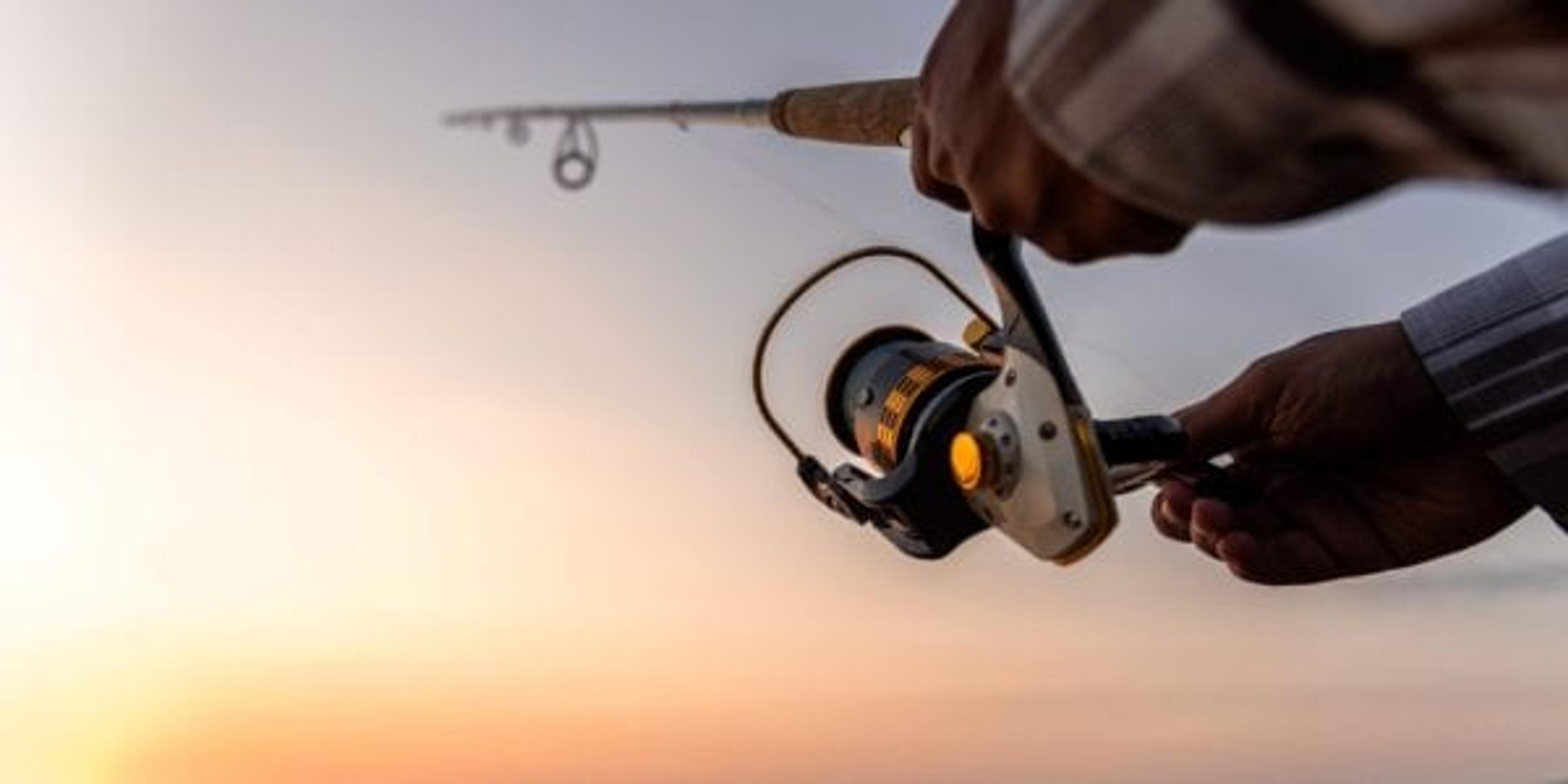 hands casting a fishing line over a lake