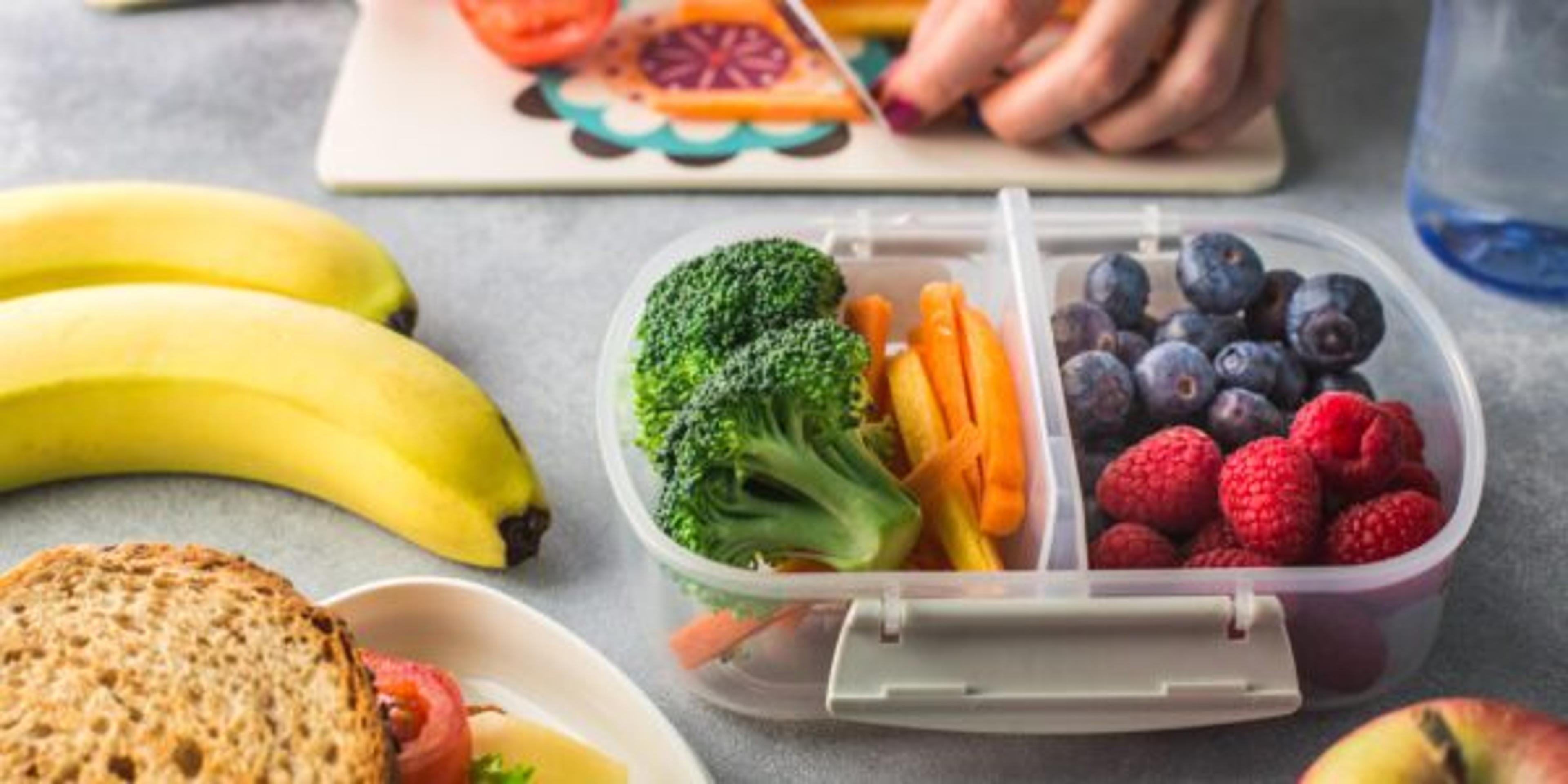 A parent chops vegetables for their child's school lunch.