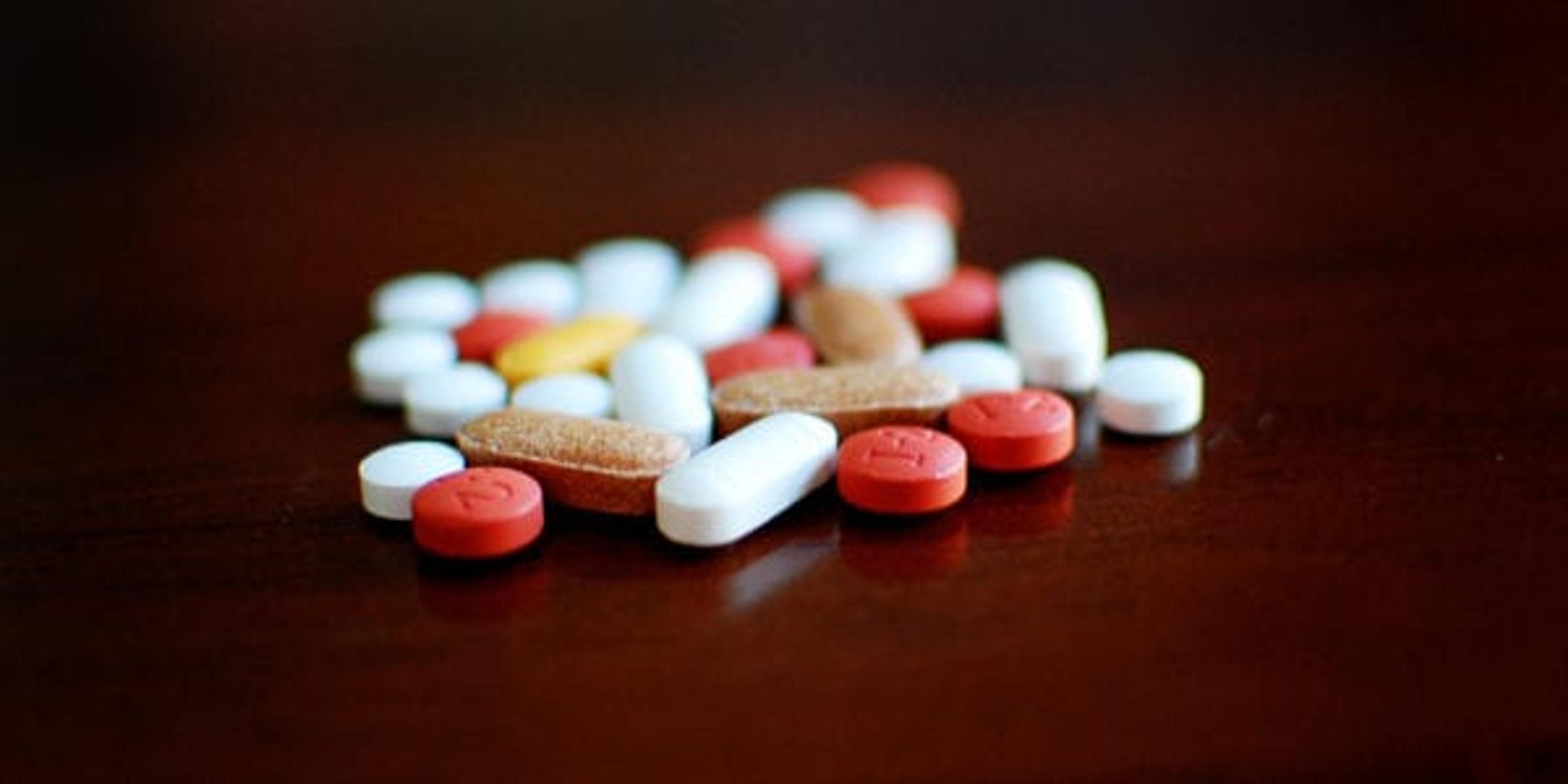 closeup of a pile of different colored pills on a table.