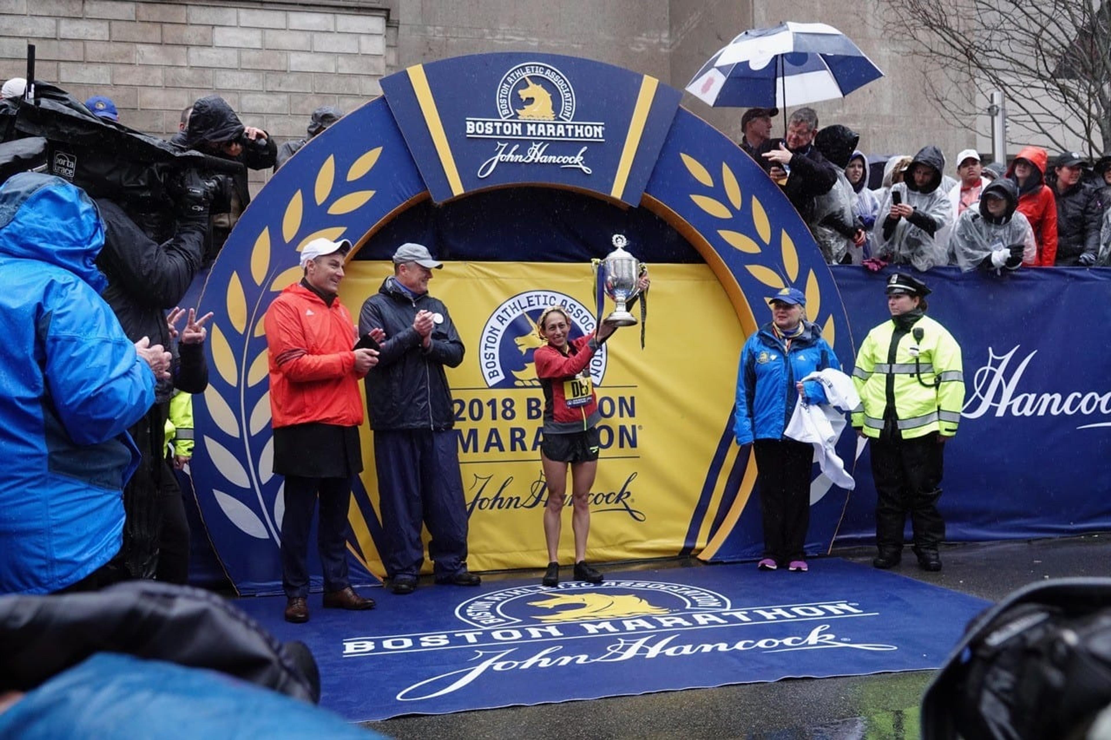 Photo of Desiree Linden holding up a trophy after winning the 2018 Boston Marathon.