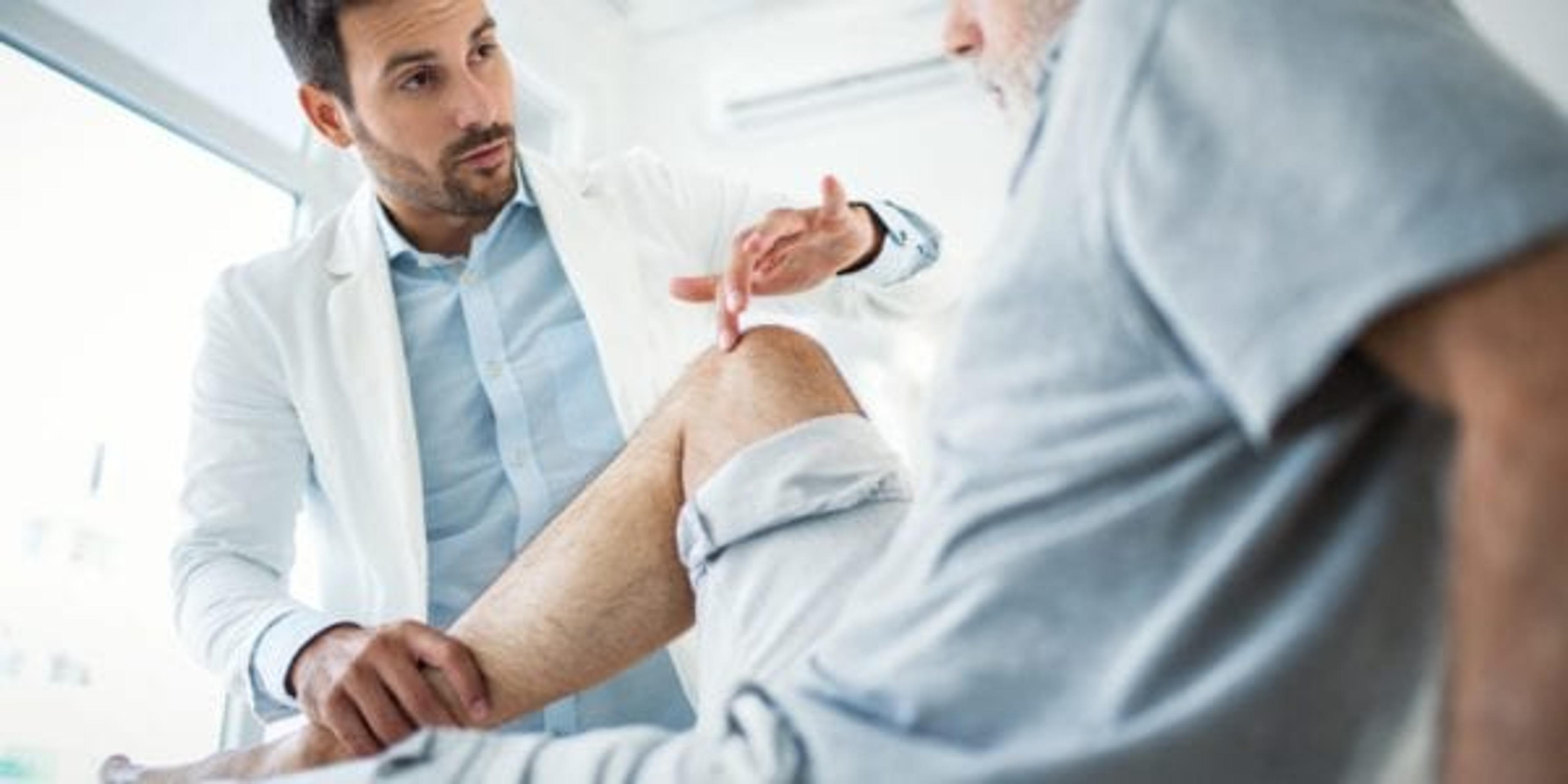 Doctor examining an older patient's knee.