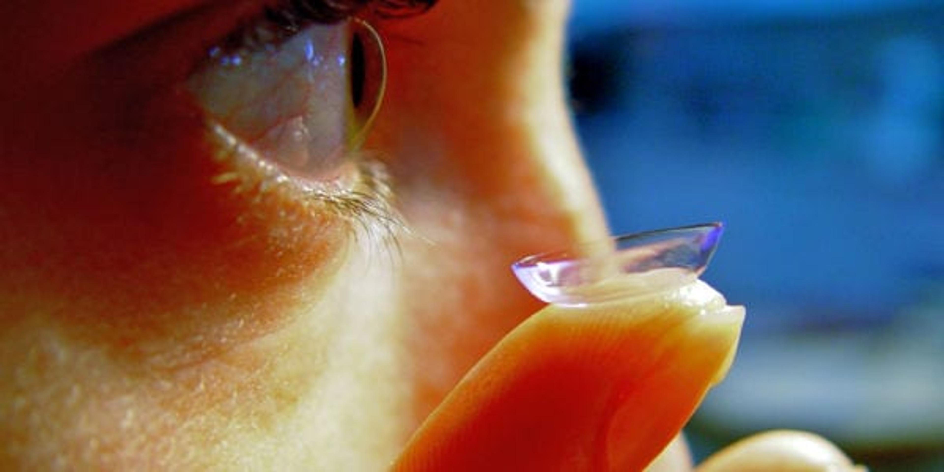 woman putting contact lens into eye