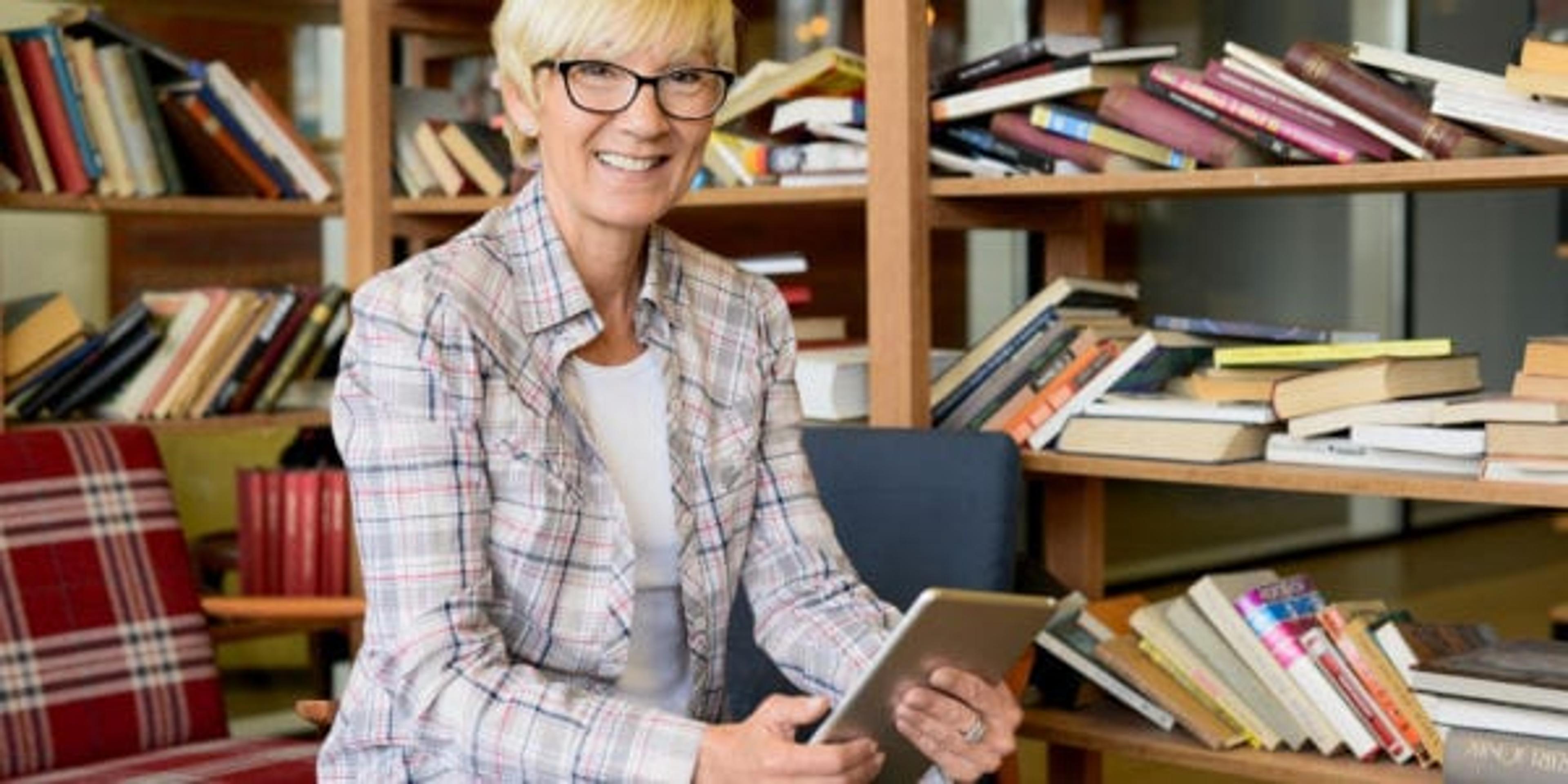 Woman with reading glasses checking a text in a library.