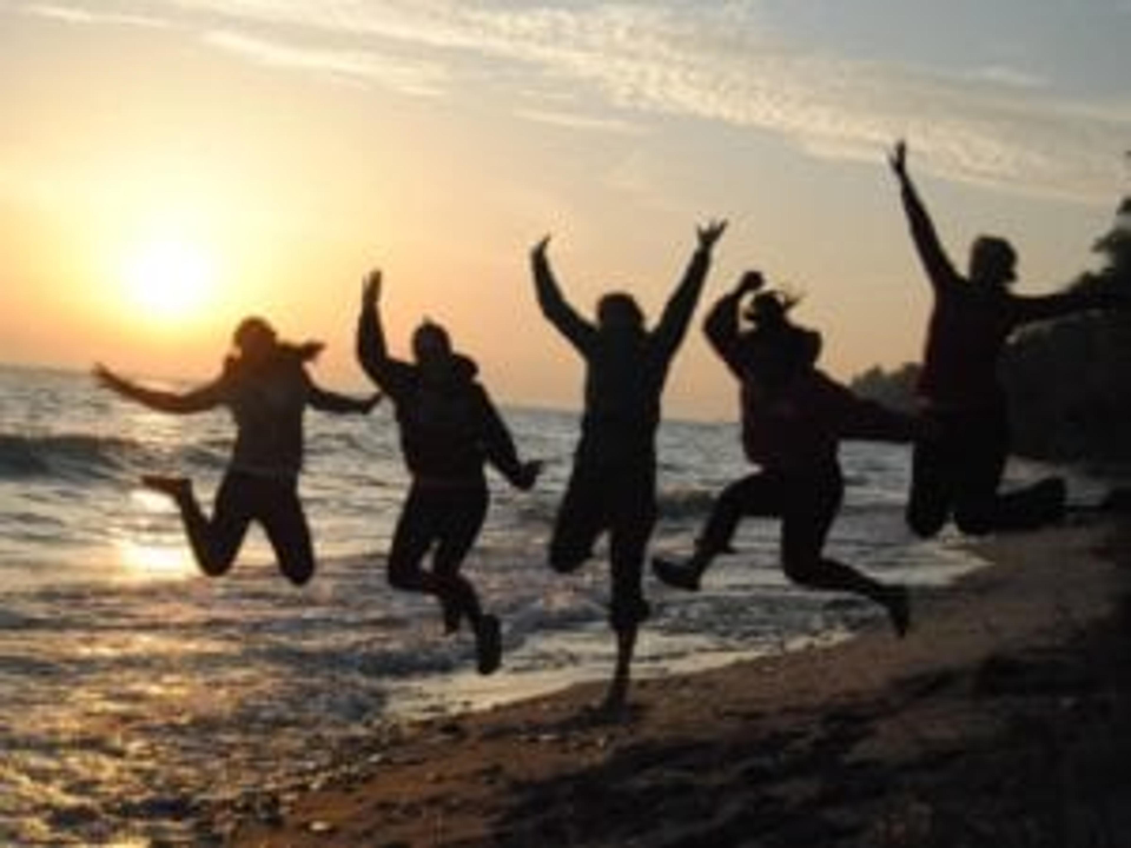 the group jumping on a beach with a sunset in the background