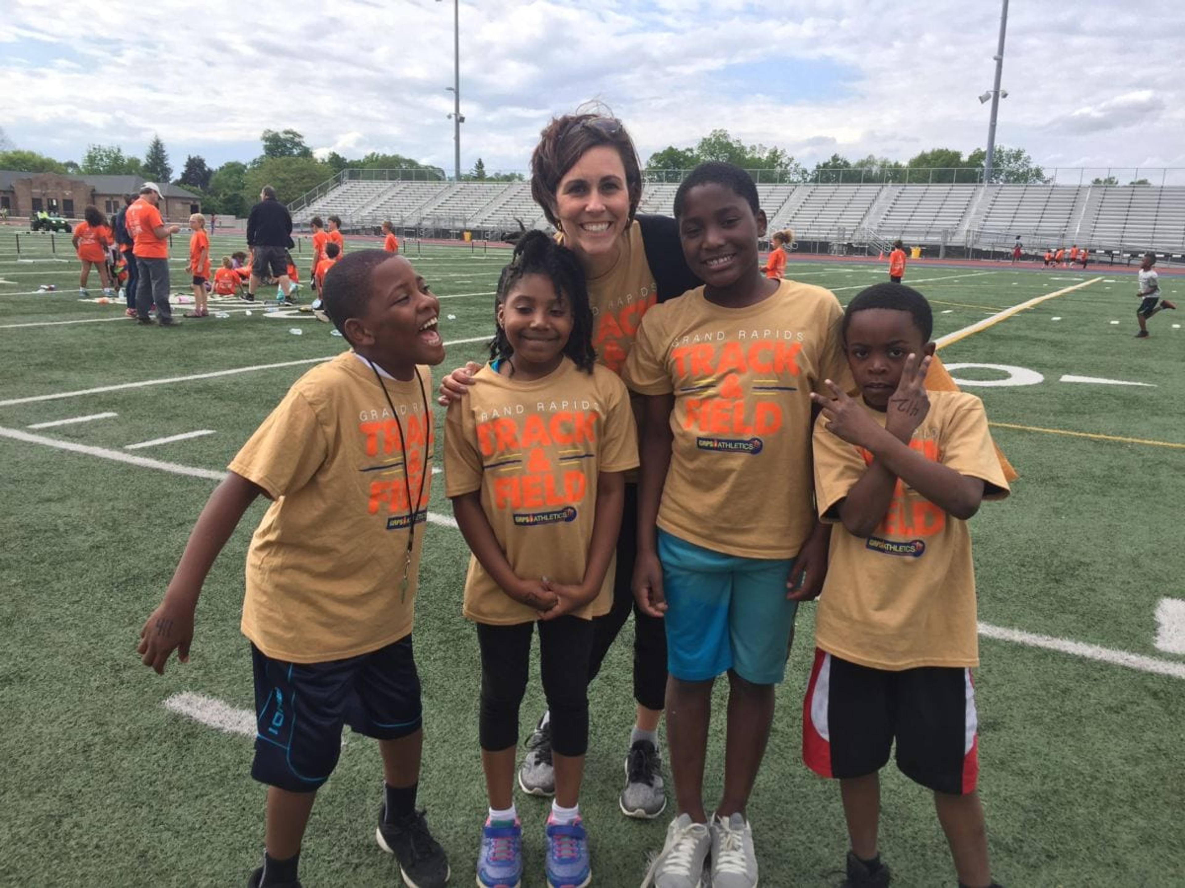 Cara Jones poses with athletes from Grand Rapids Public Schools during a track meet.