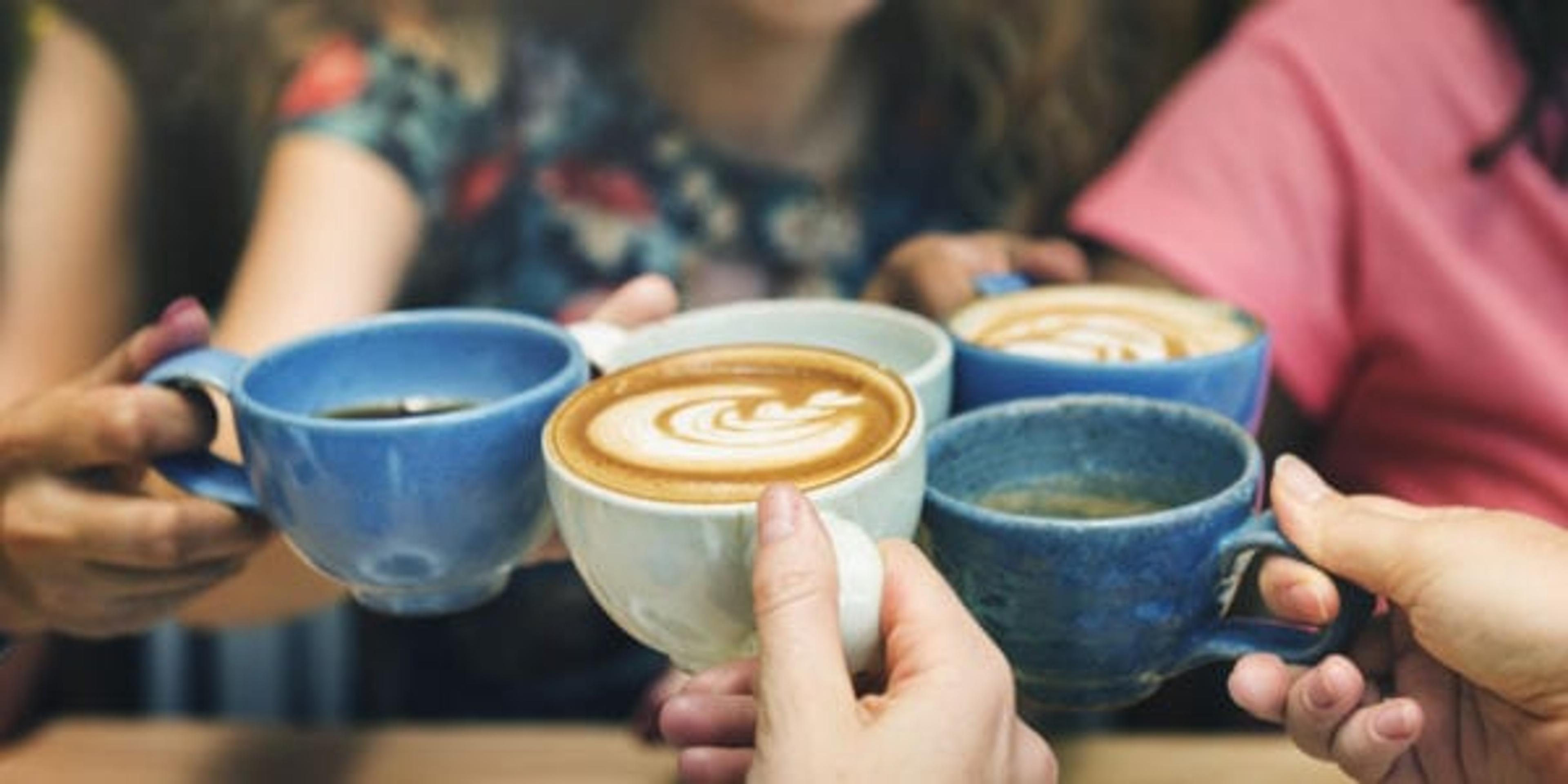 Young women toasting with coffee cups.