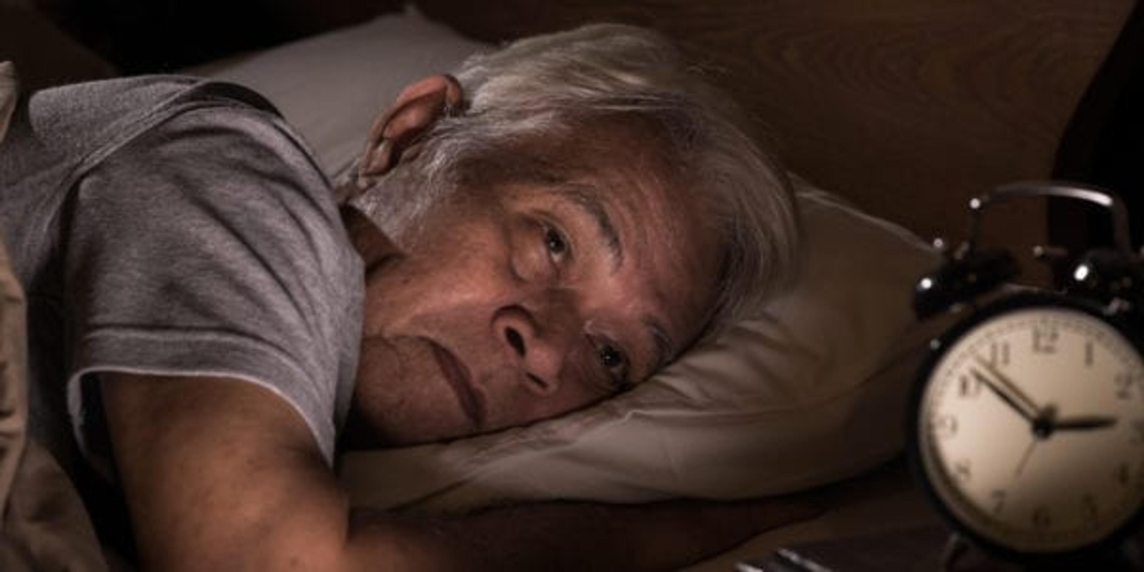 A depressed senior man lying in bed cannot sleep from insomnia