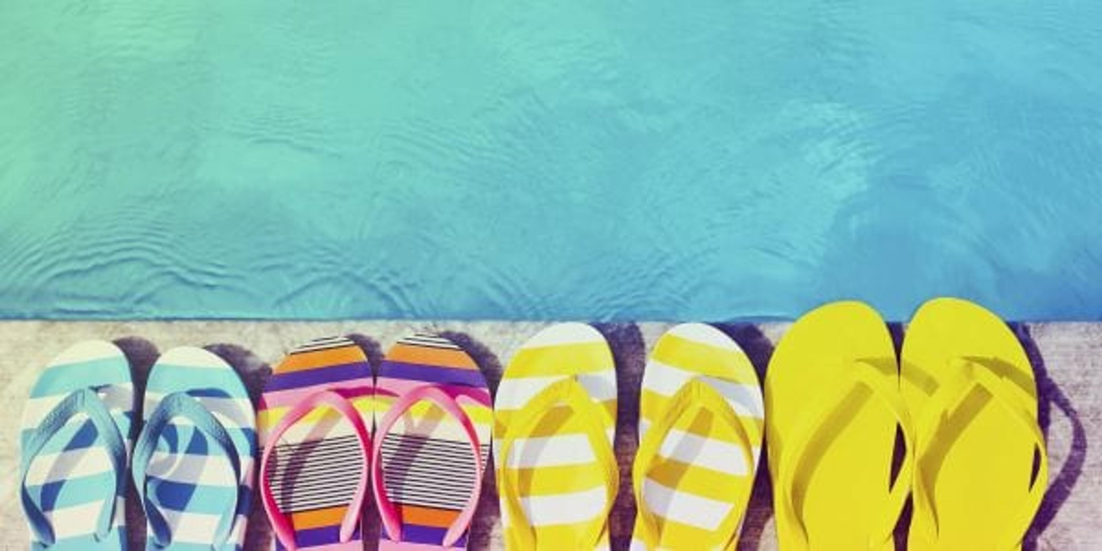 four pairs of flip flops on the edge of the pool