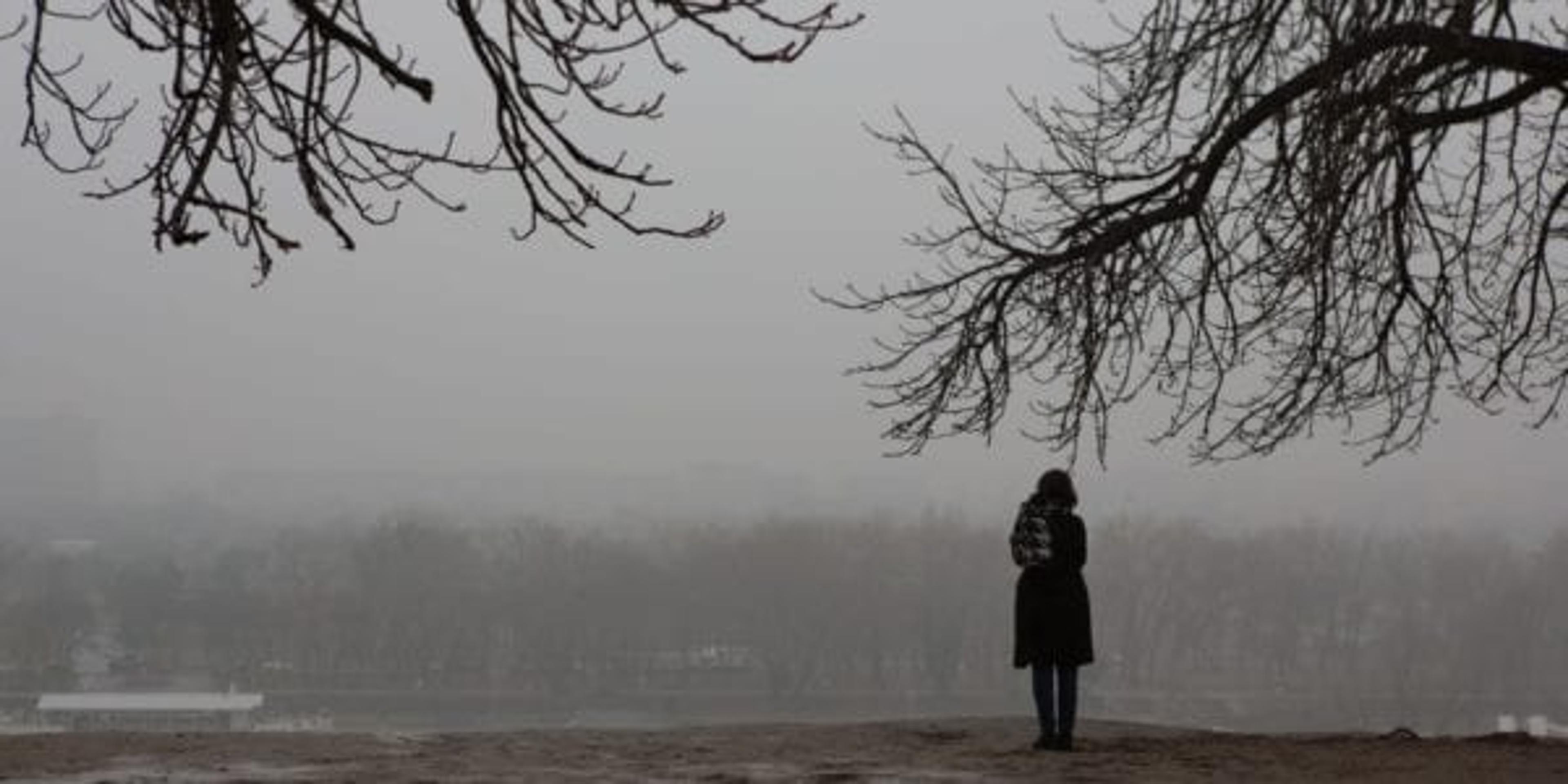Girl standing alone on a cloudy gloomy day