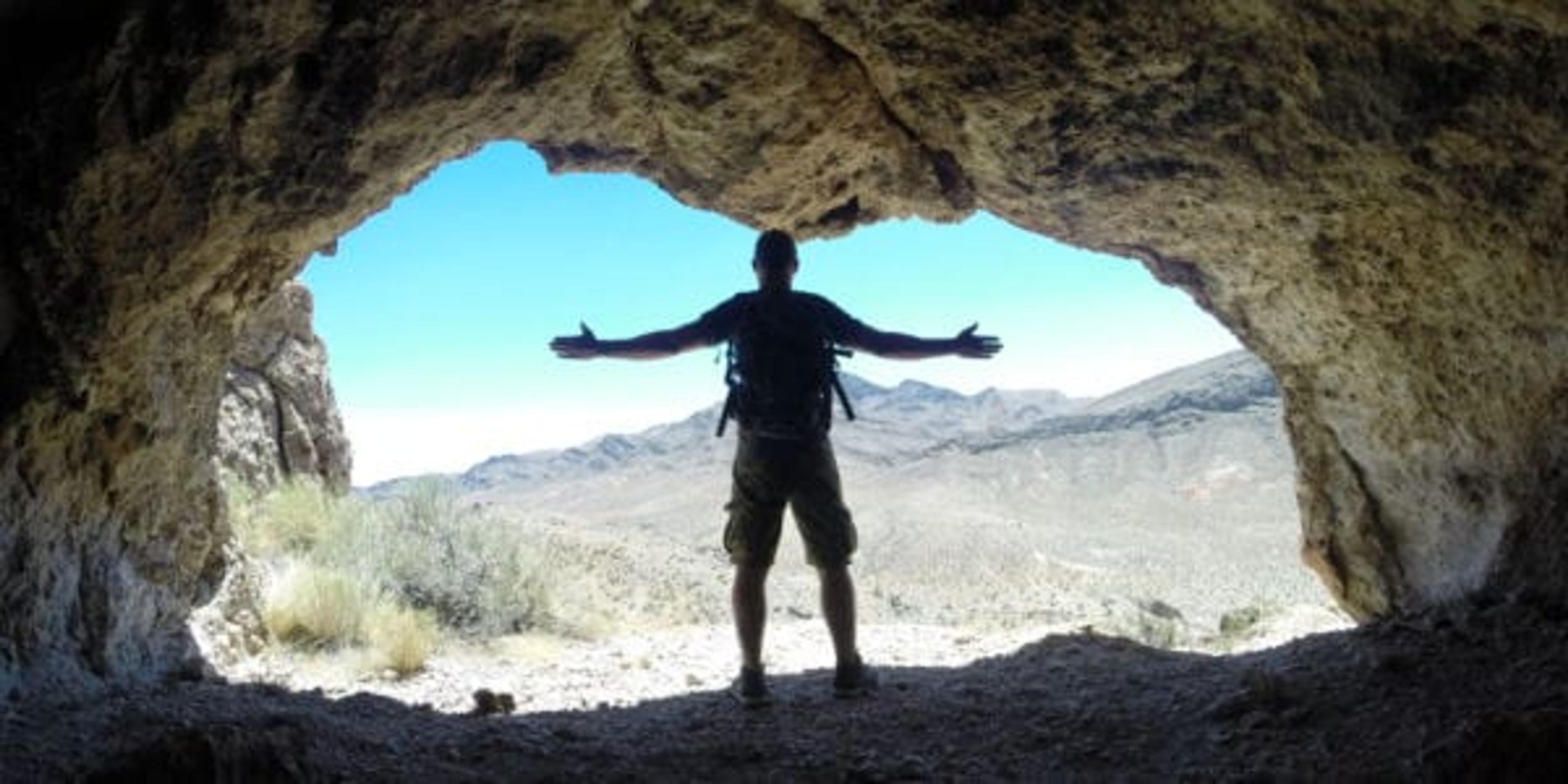 man standing in a cave with a backpack