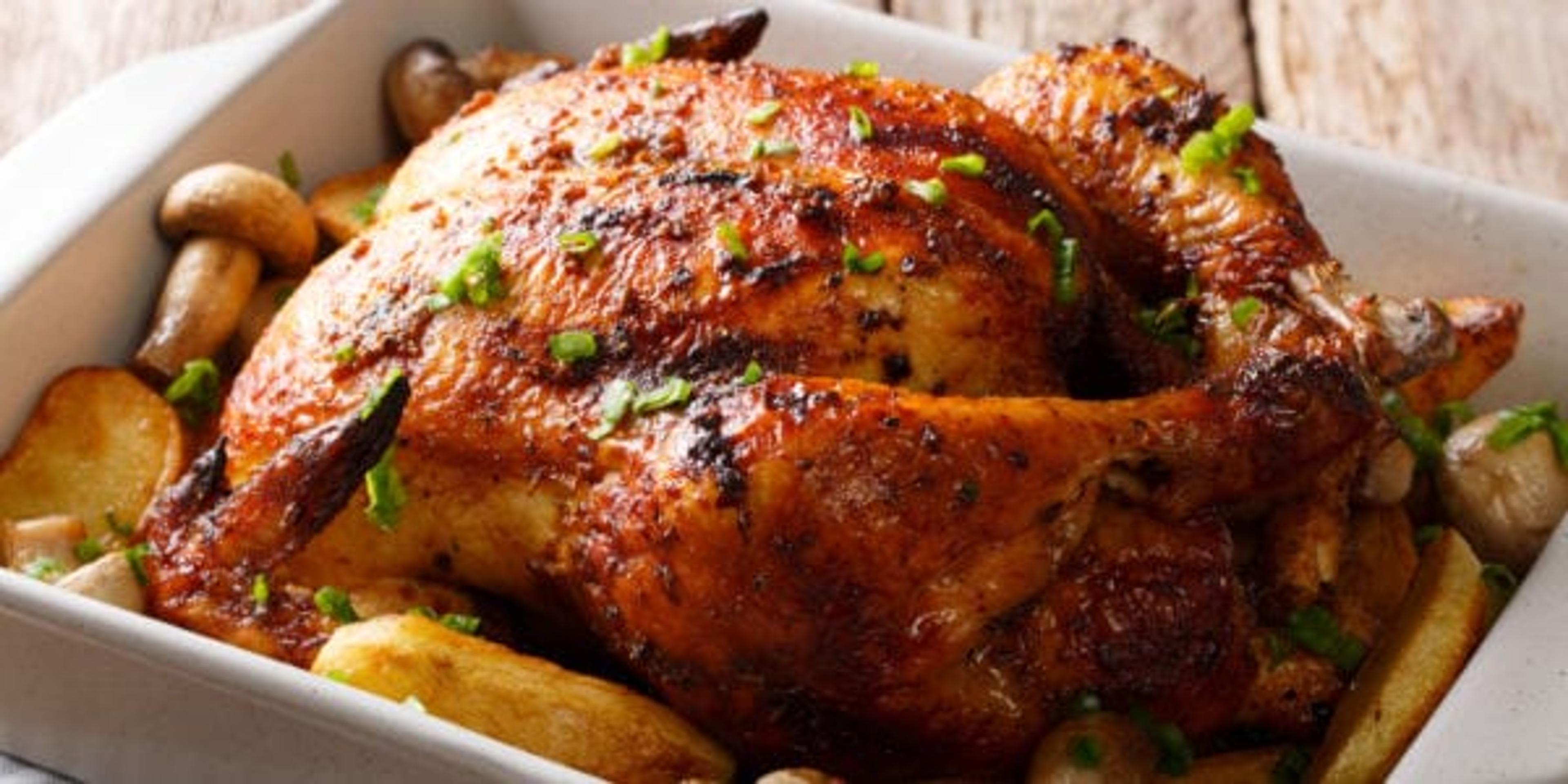 Whole grilled chicken with mushrooms and potatoes close-up.