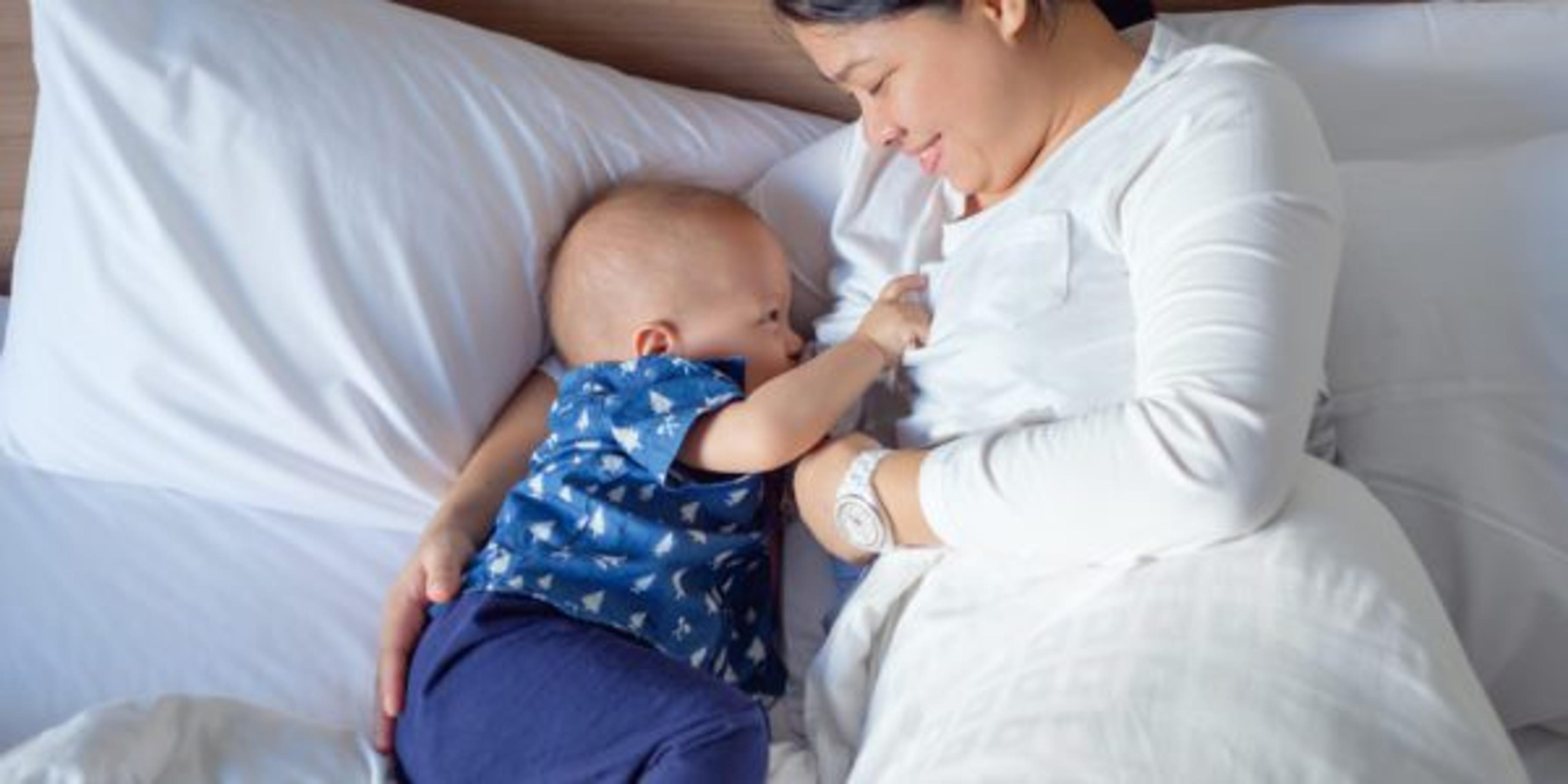 Asian mother is breastfeeding Cute little Asian 14 months / 1 year old toddler baby boy child in bed