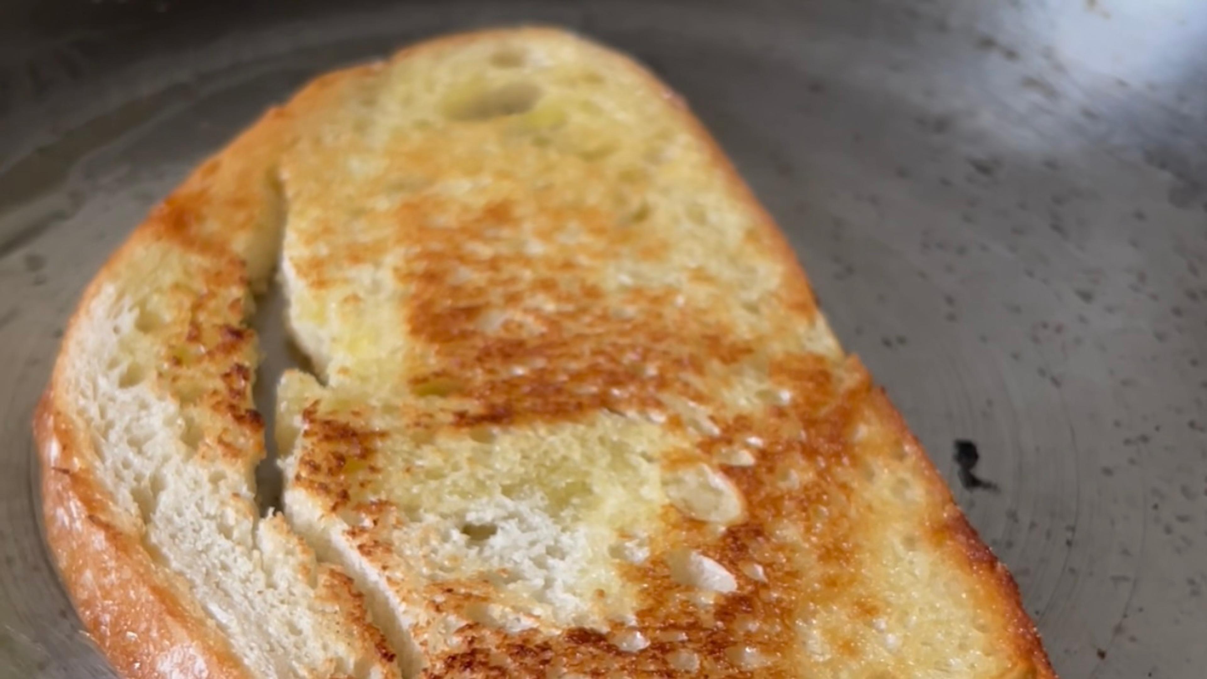 Sourdough bread toasting in oil in a skillet.