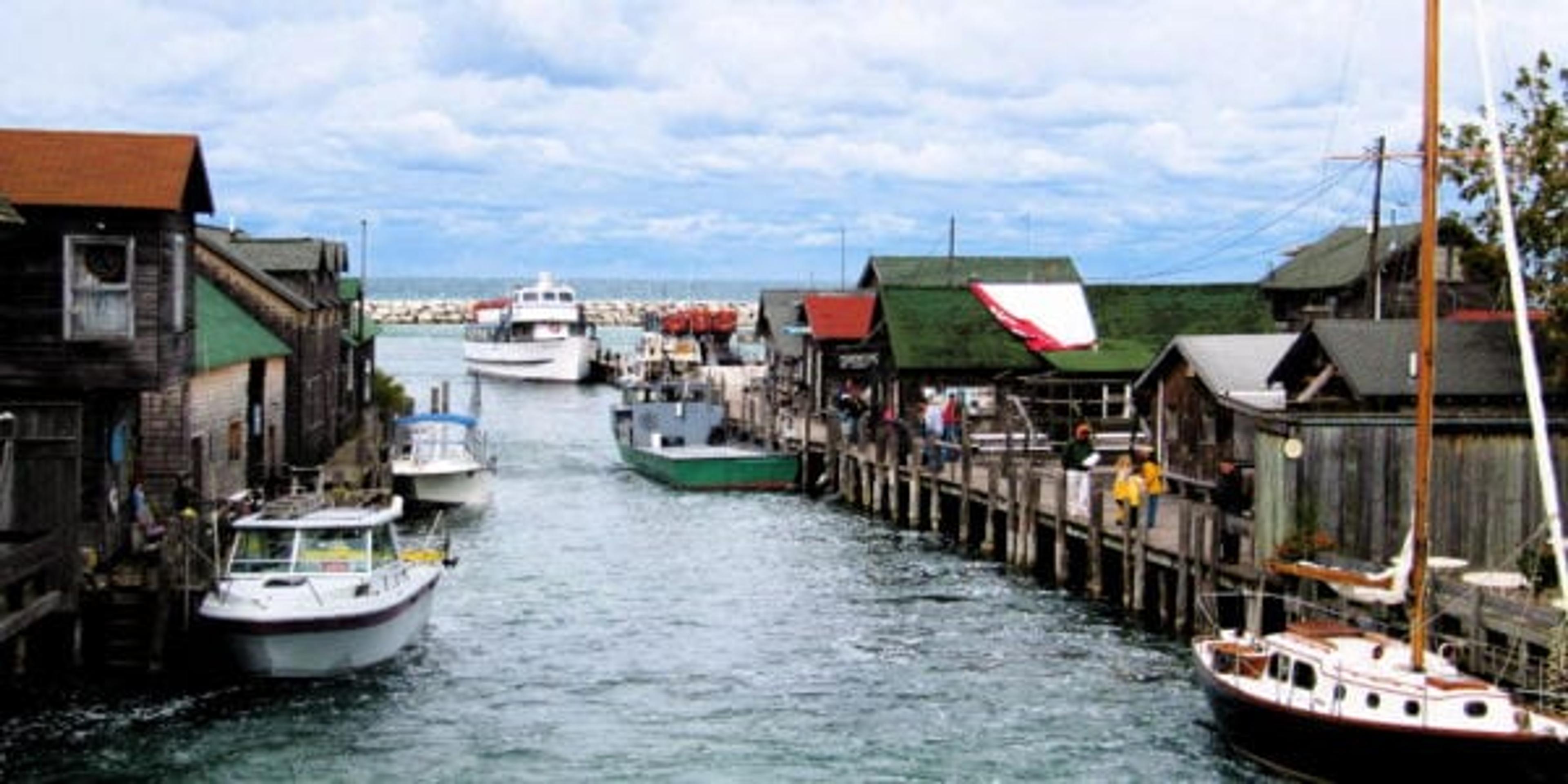 Fishtown pictured on a summer day with the Leland River's aqua blue waters gently rolling over the historical dam and mixing with the pristine waters of Lake Michigan