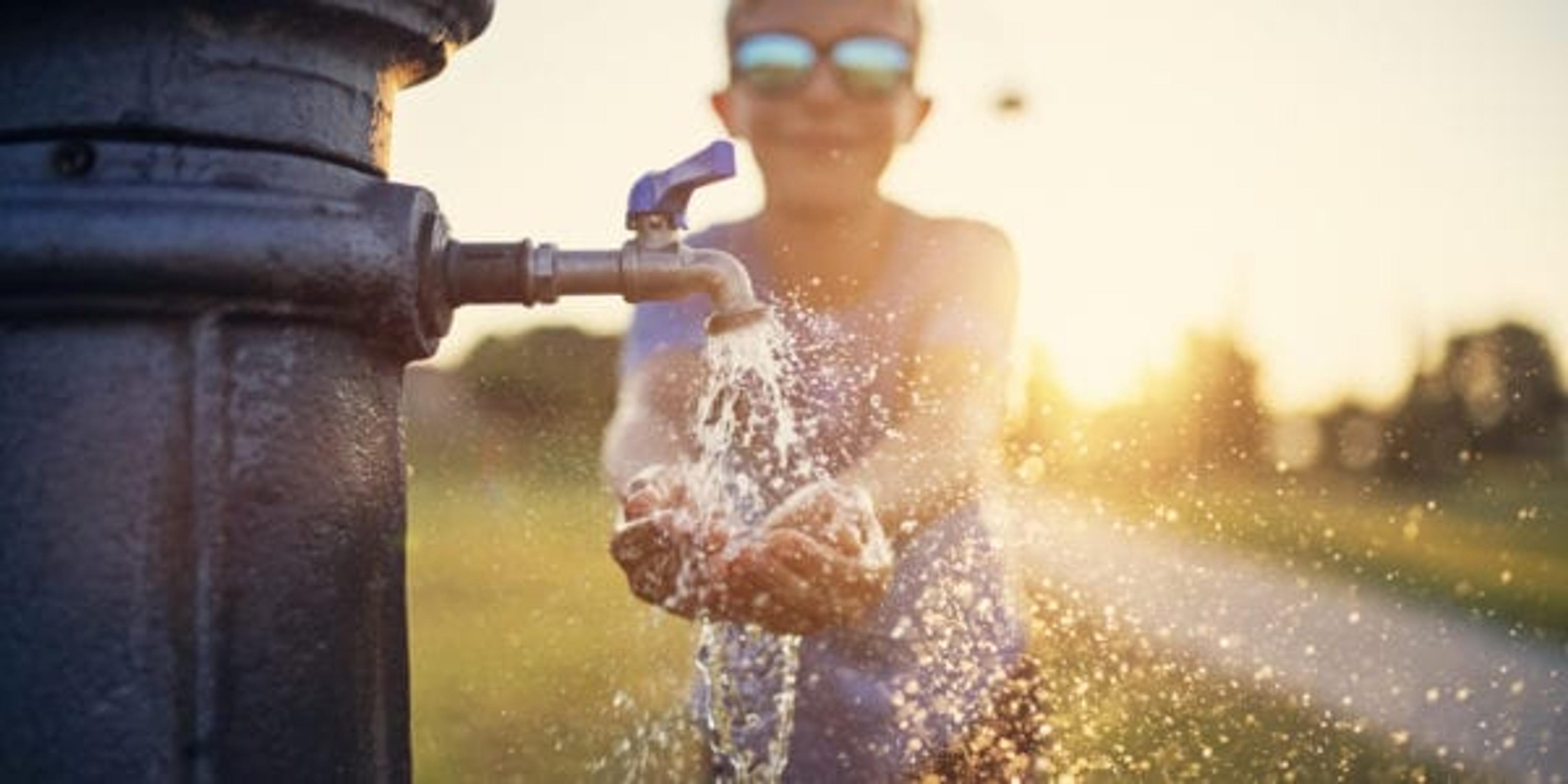 Little thirsty boy drinking water from public fountain. Nikon D850