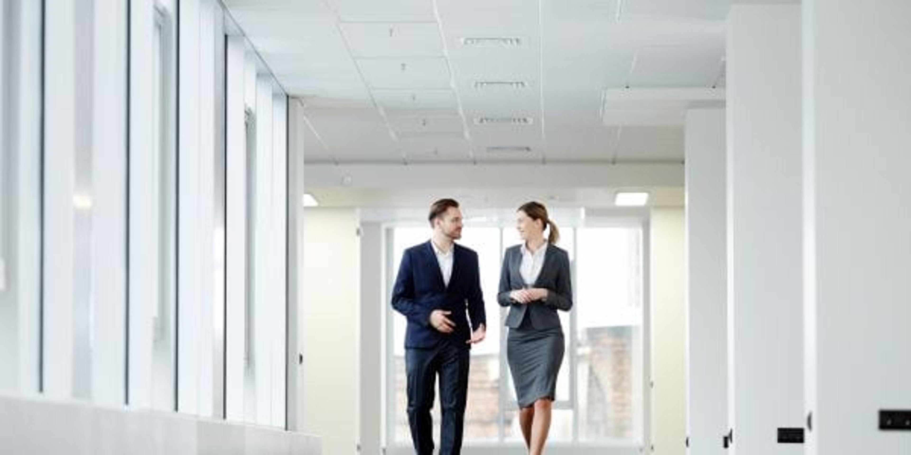 Confident business colleagues walking down in office building and talking