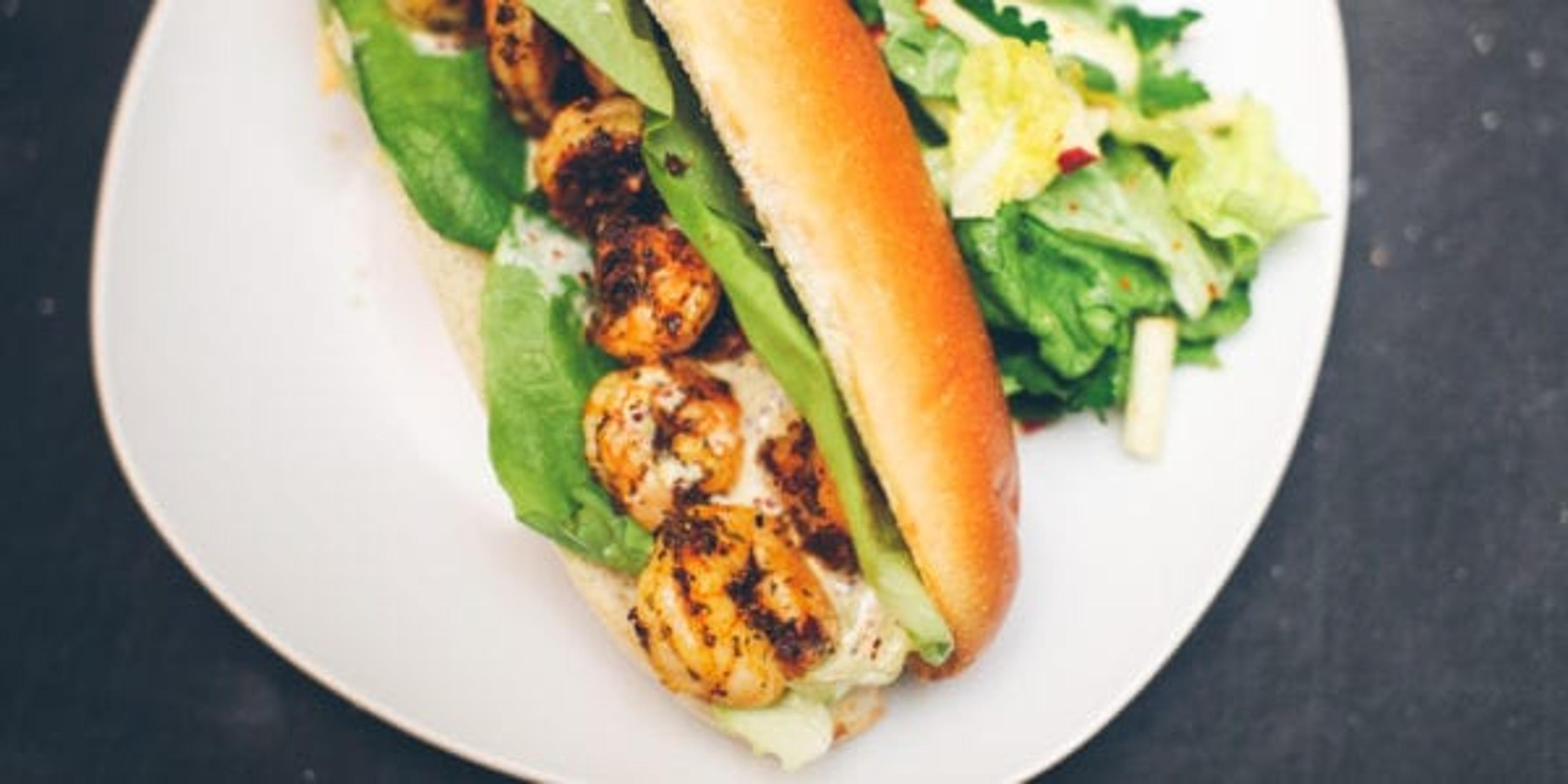 a sandwich open on a white plate with salad next to it