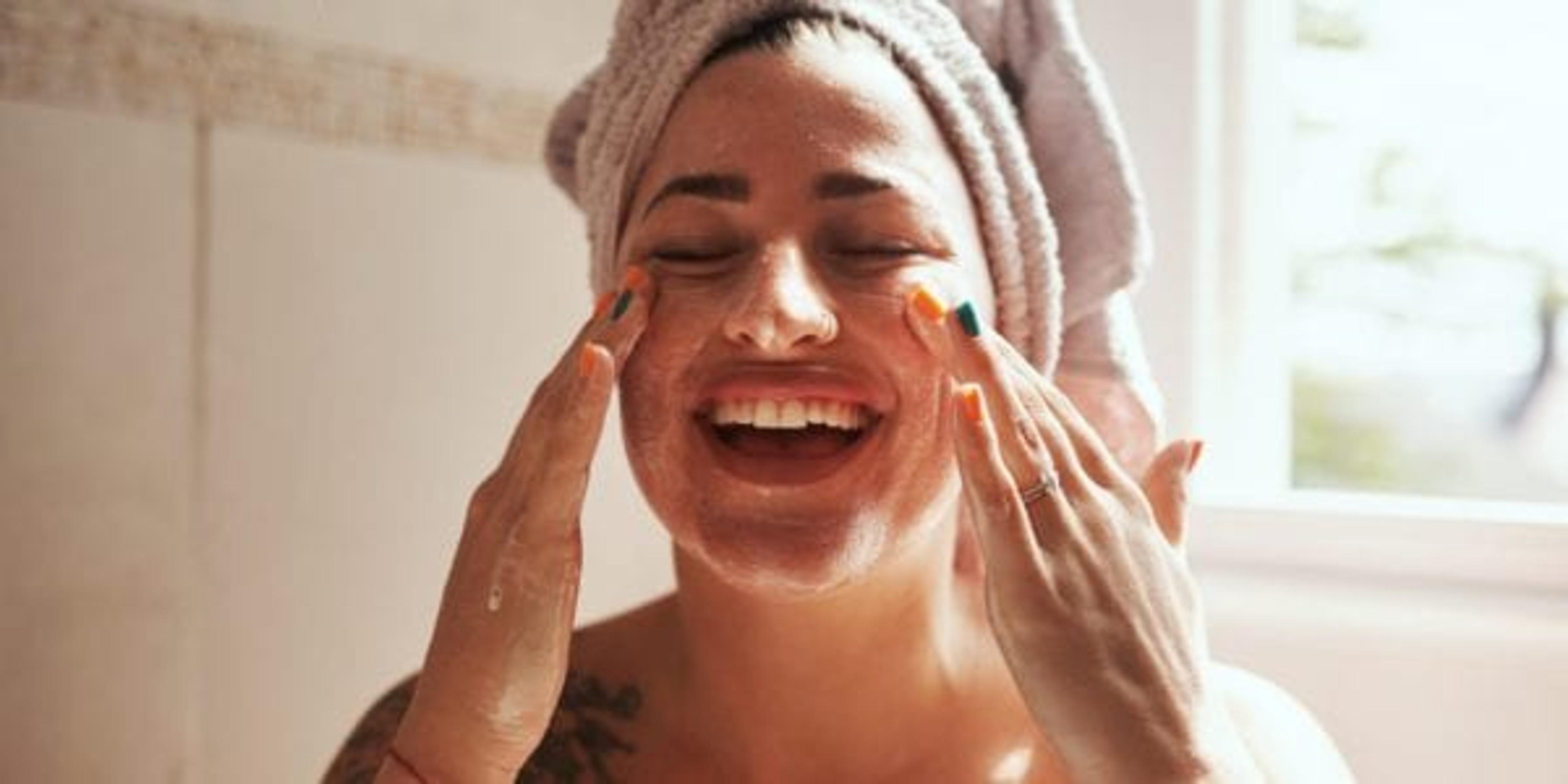 Shot of a young woman giving herself a facial at home