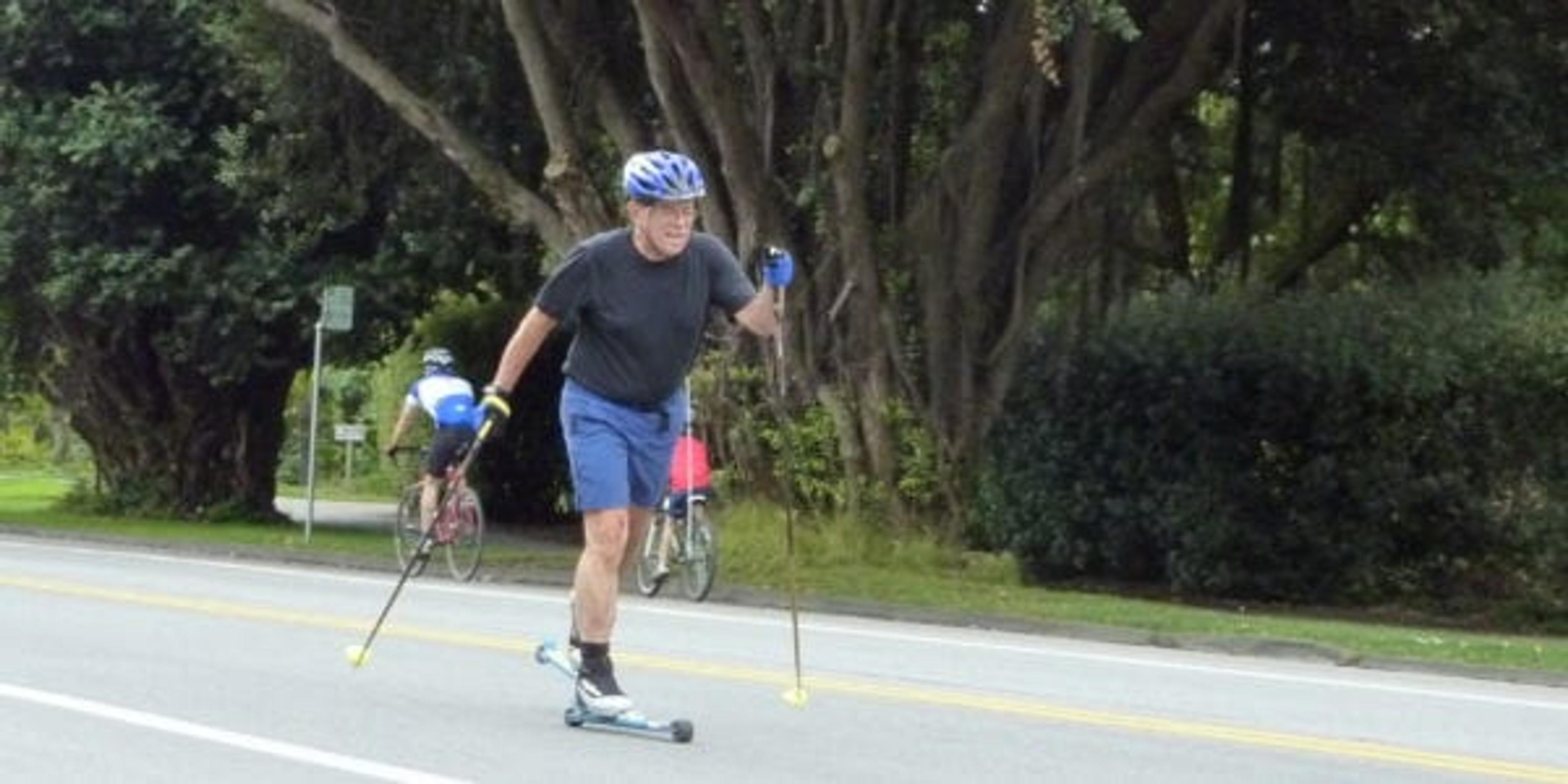 Man roller skiing down a street.