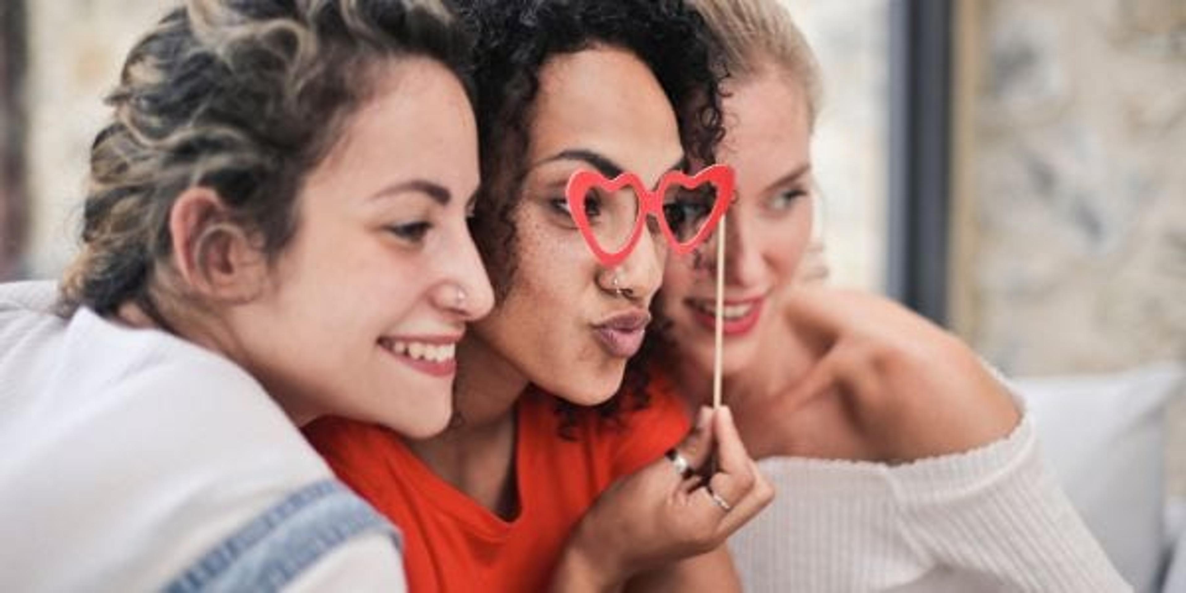Three women posing for a picture with heart glasses on