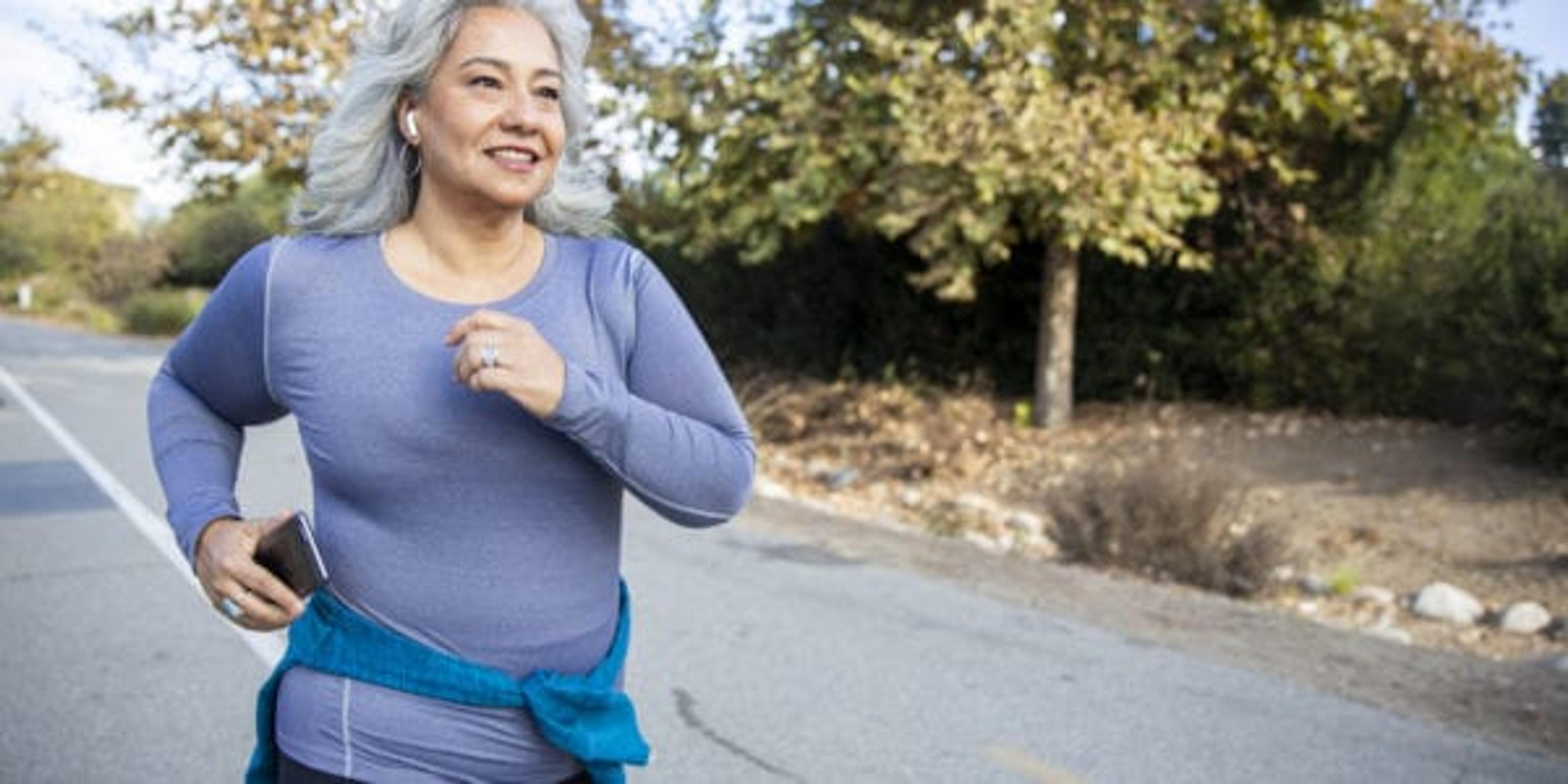 A mature Mexican woman jogging on a trail