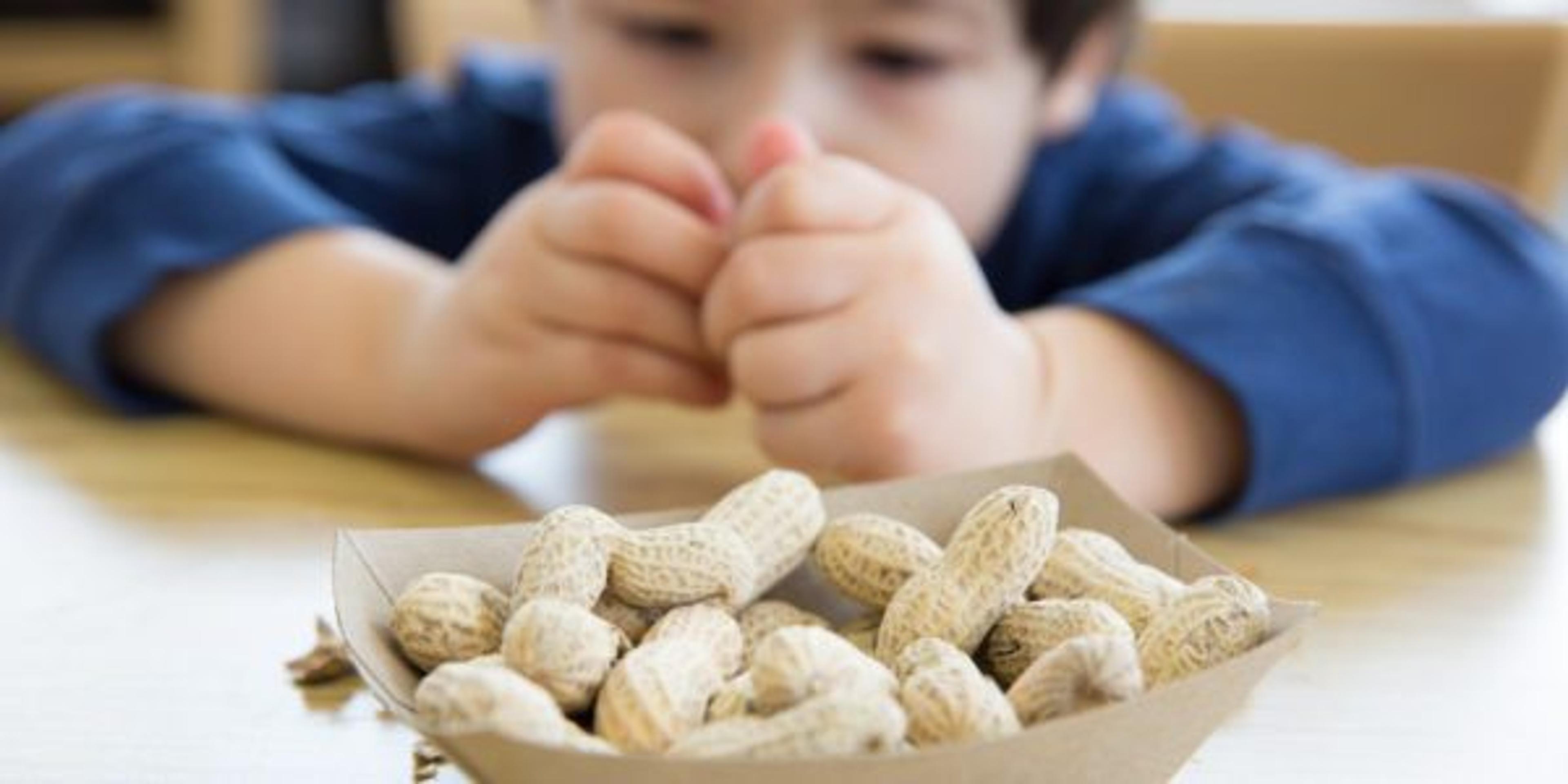 Little boy opening up peanuts to eat in a restaurant