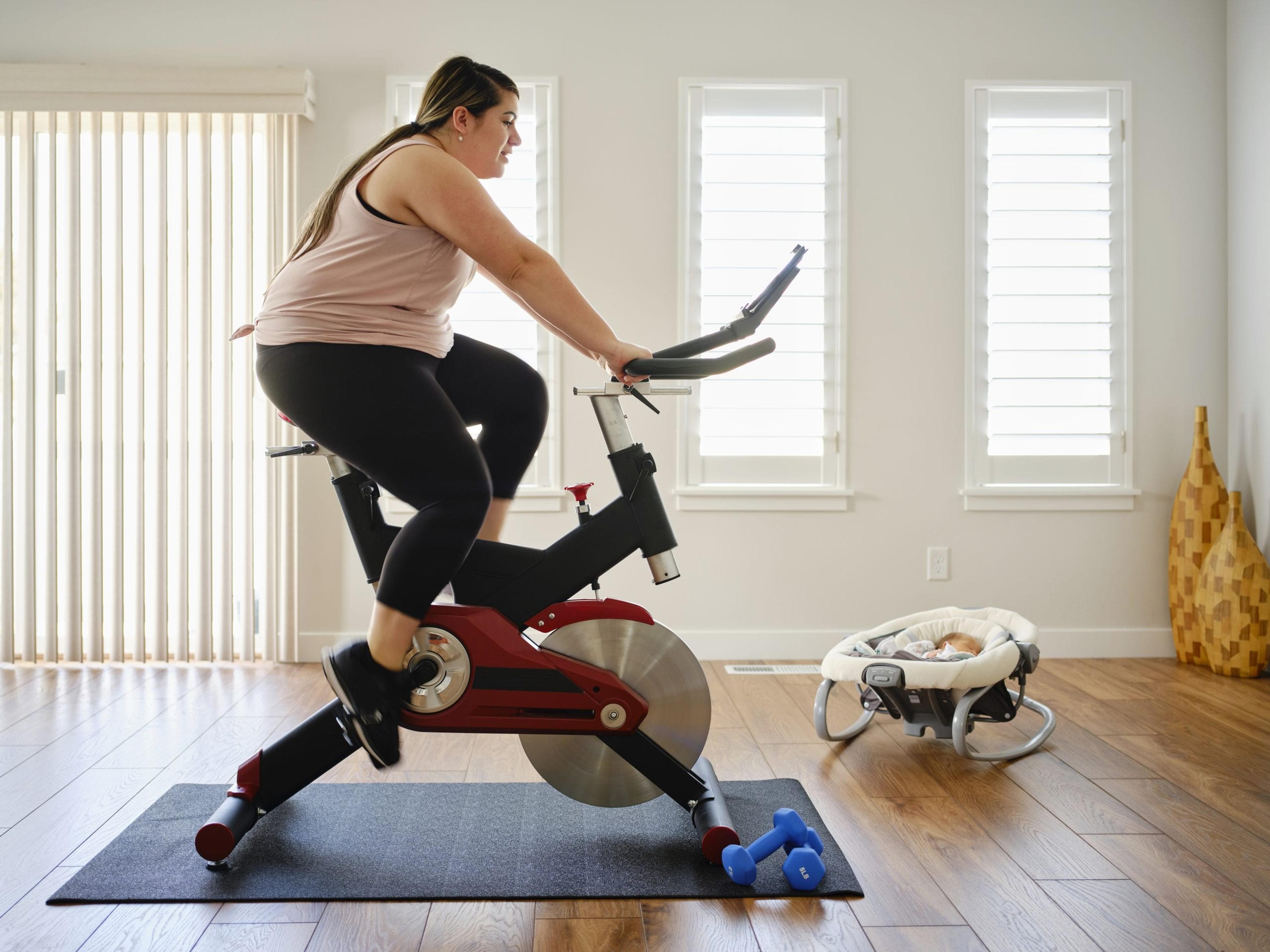 A young mother exercising in her home on an exercise bike.