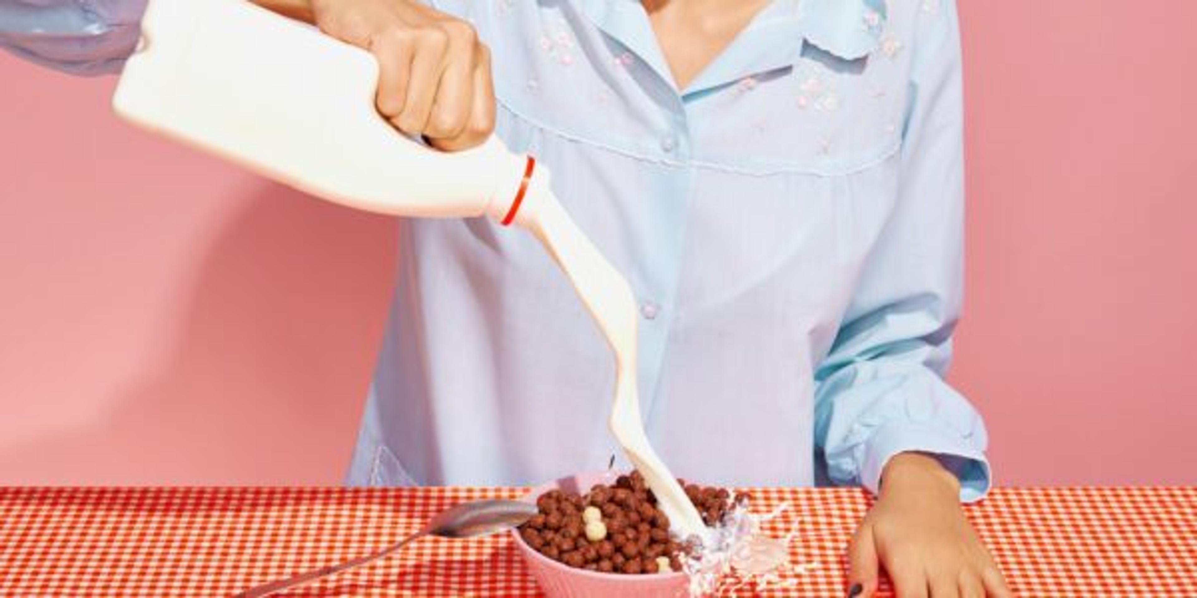 Cropped portrait of woman making cornflakes with milk. Retro 80s, 70s style. Complementary colors. Concept of art, beauty, minimalism