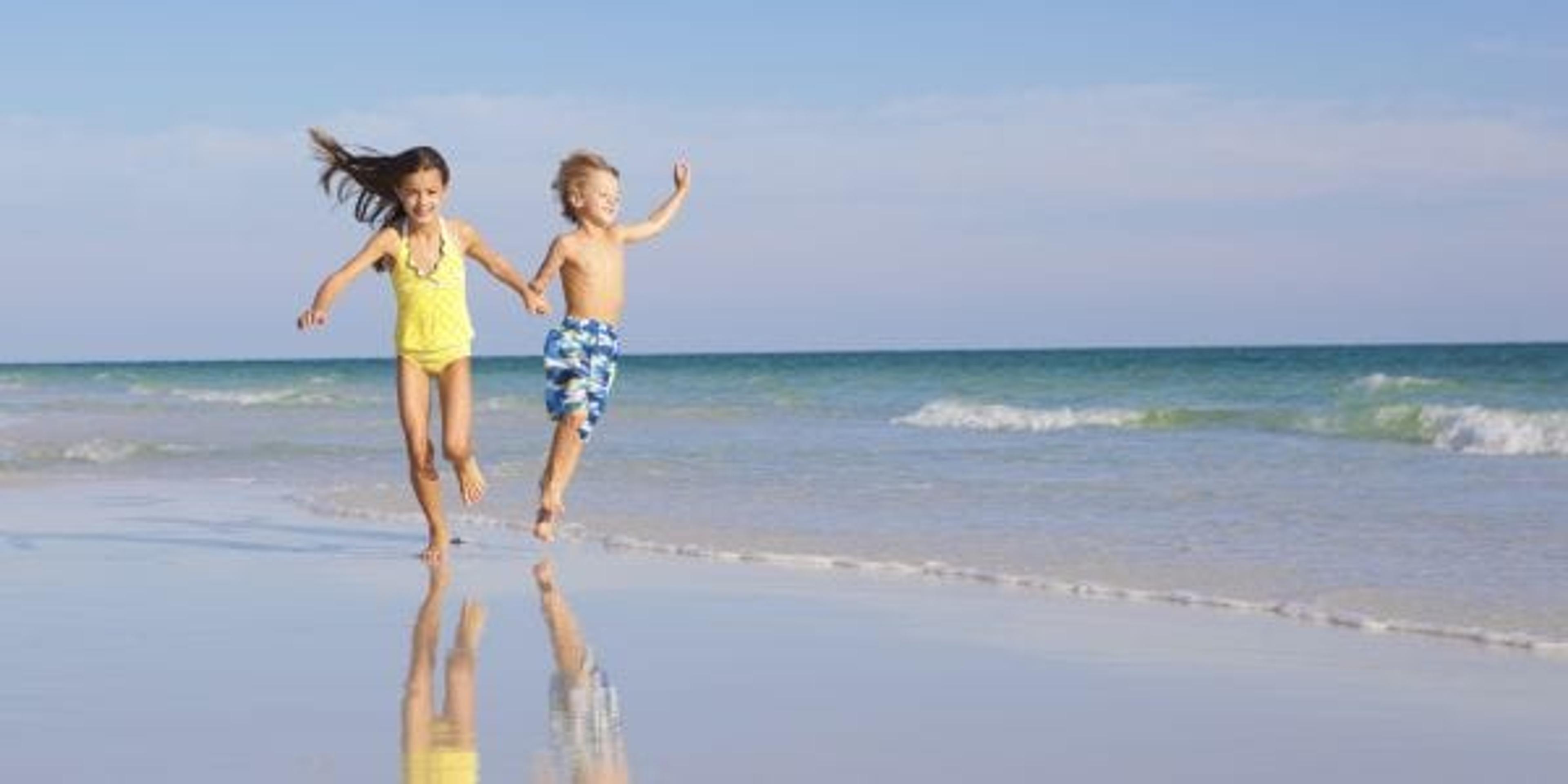 Two children running along the shoreline.