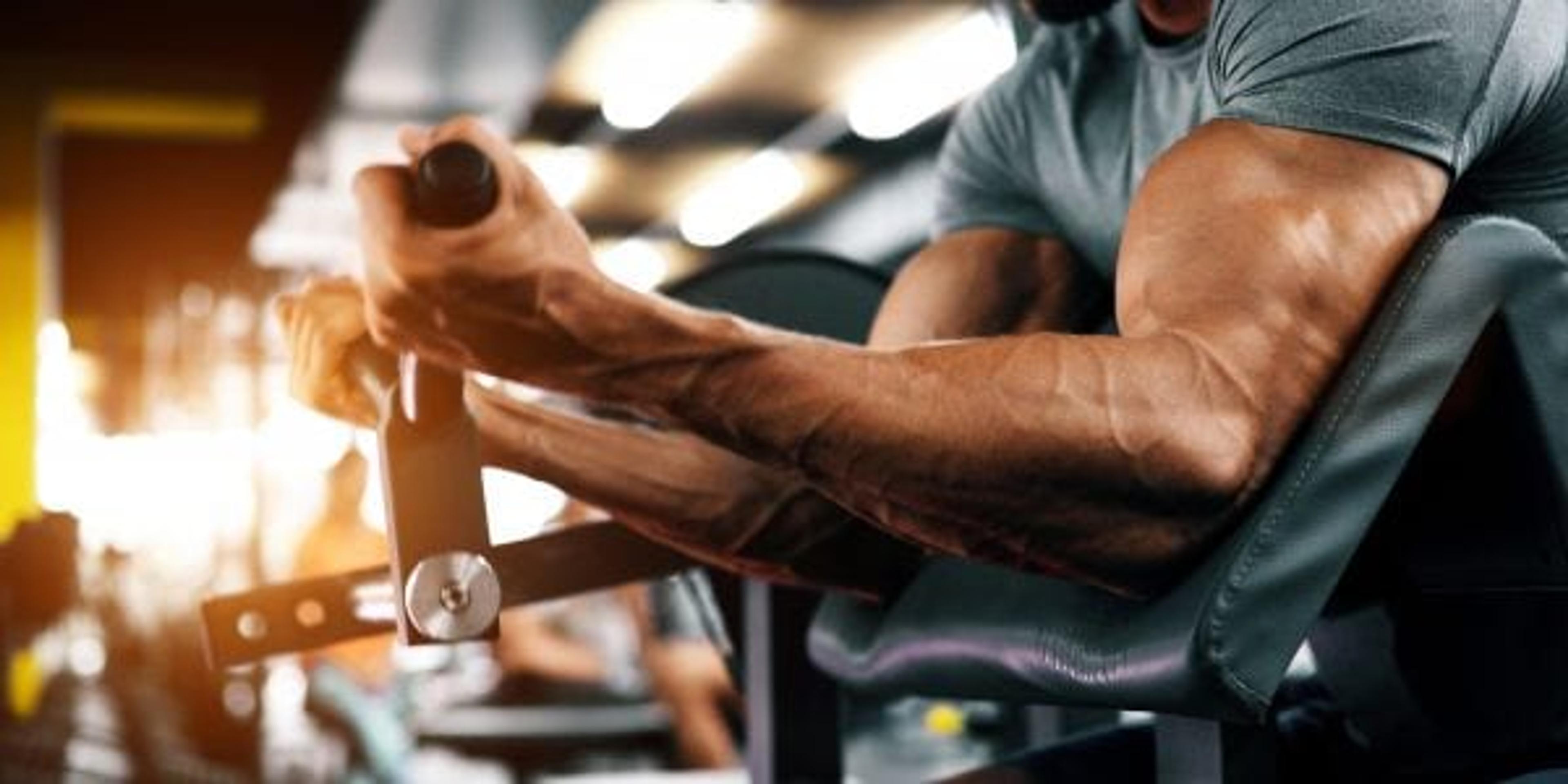 Muscular bodybuilder guy doing exercises with dumbbells in gym