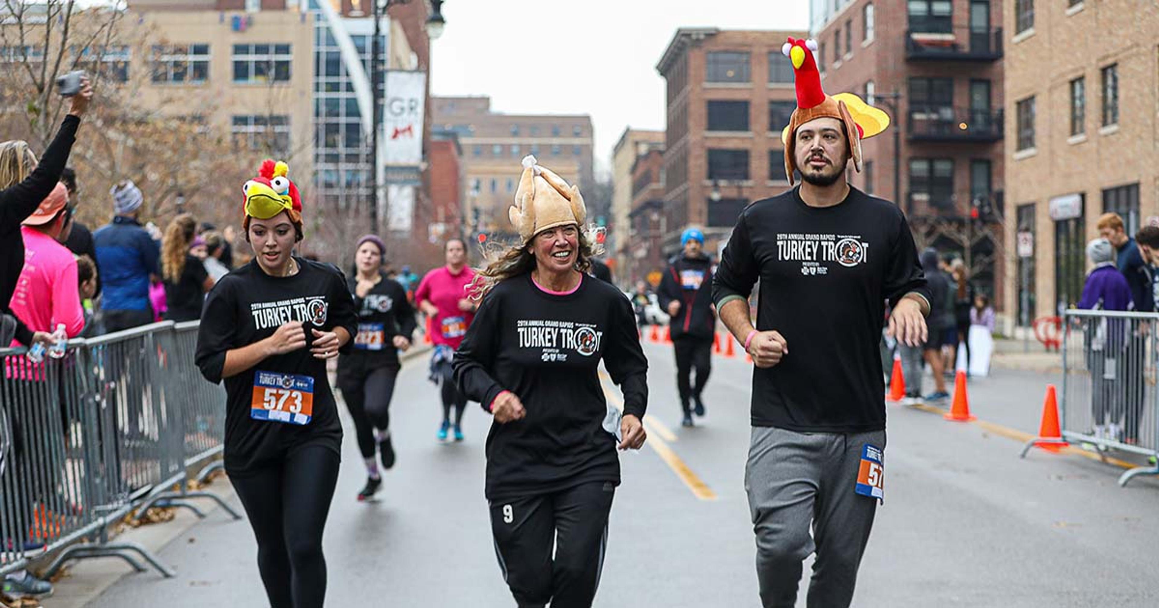 Three runners wearing turkey hats participate in the 2021 Grand Rapids Turkey Trot.