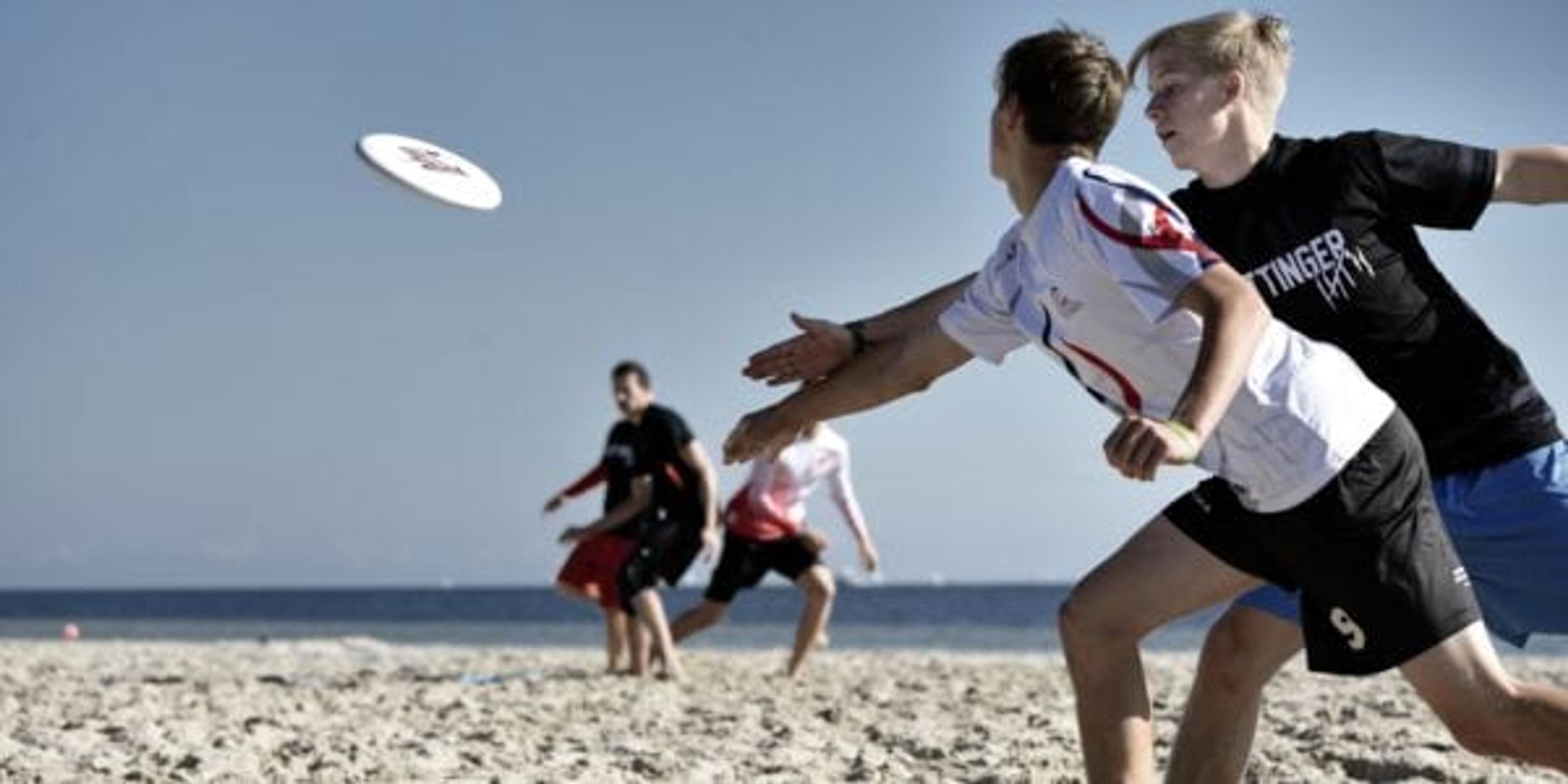 boys playing frisbee on a beach