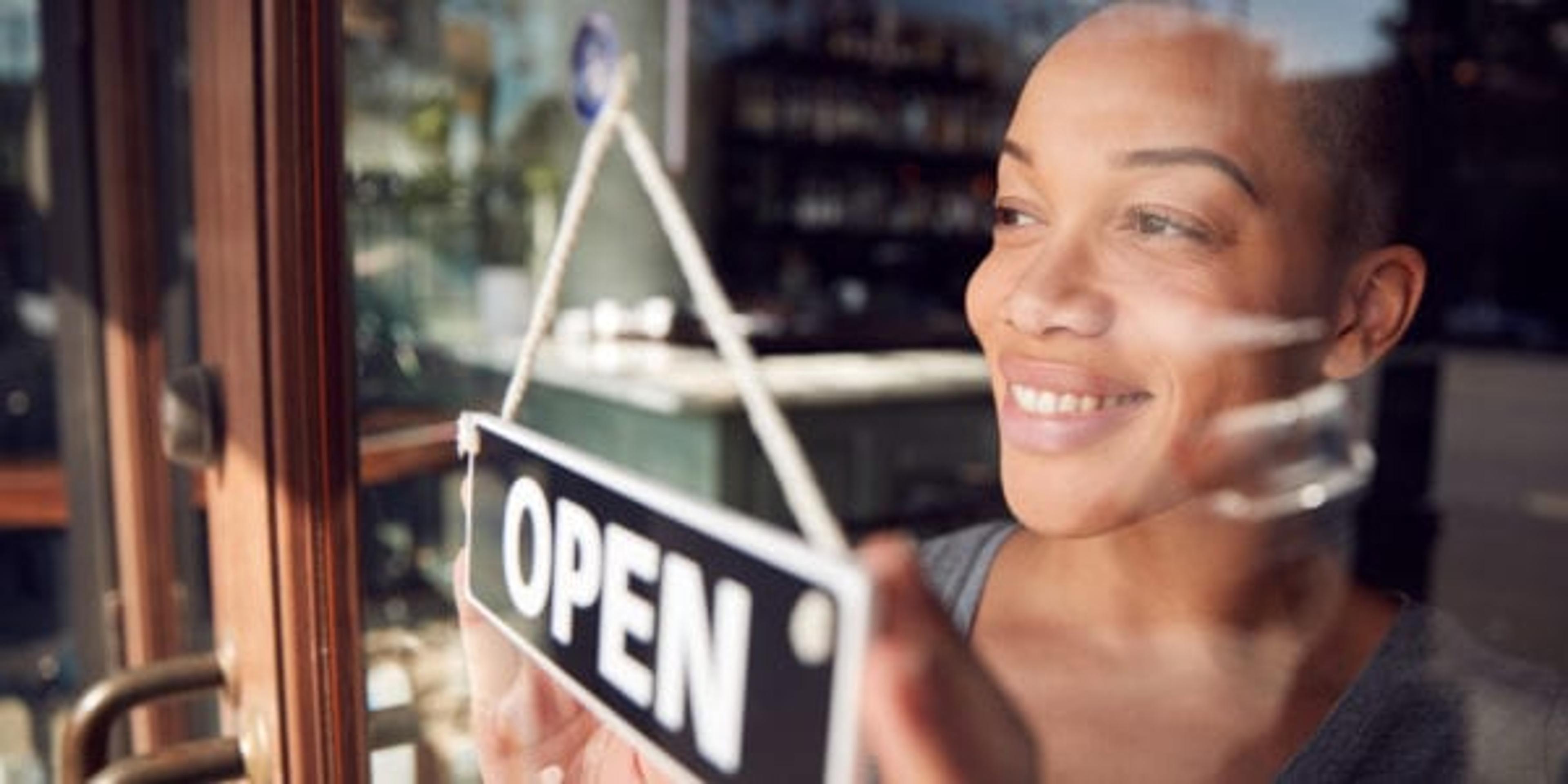 Black female business owner puts an open sign in the window