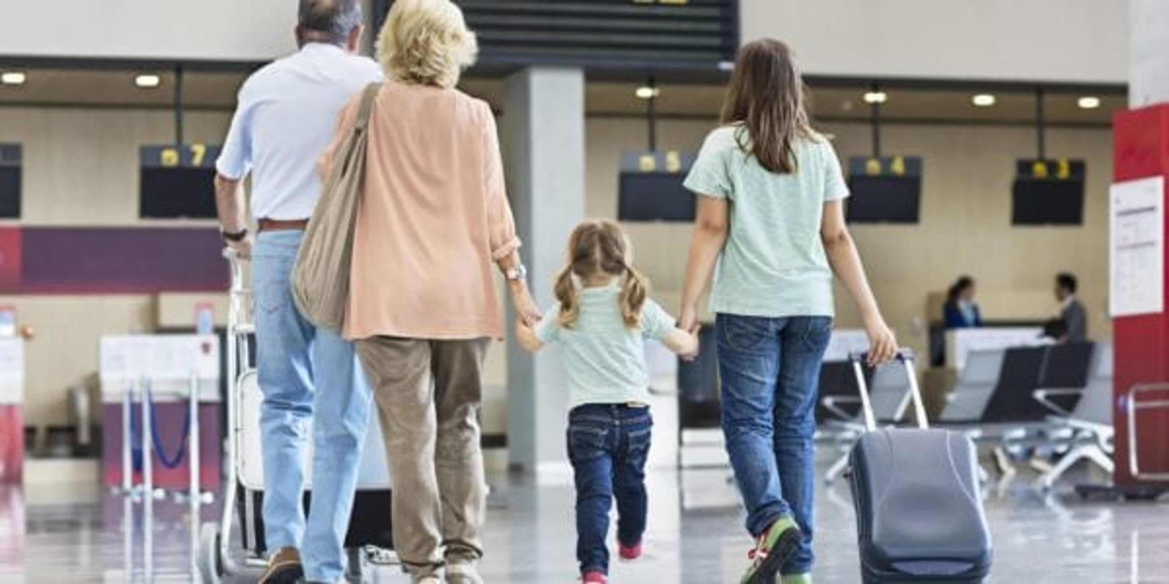 Grandparents with granddaughters walking to the check in at the airport, They all travelling together on holidays.