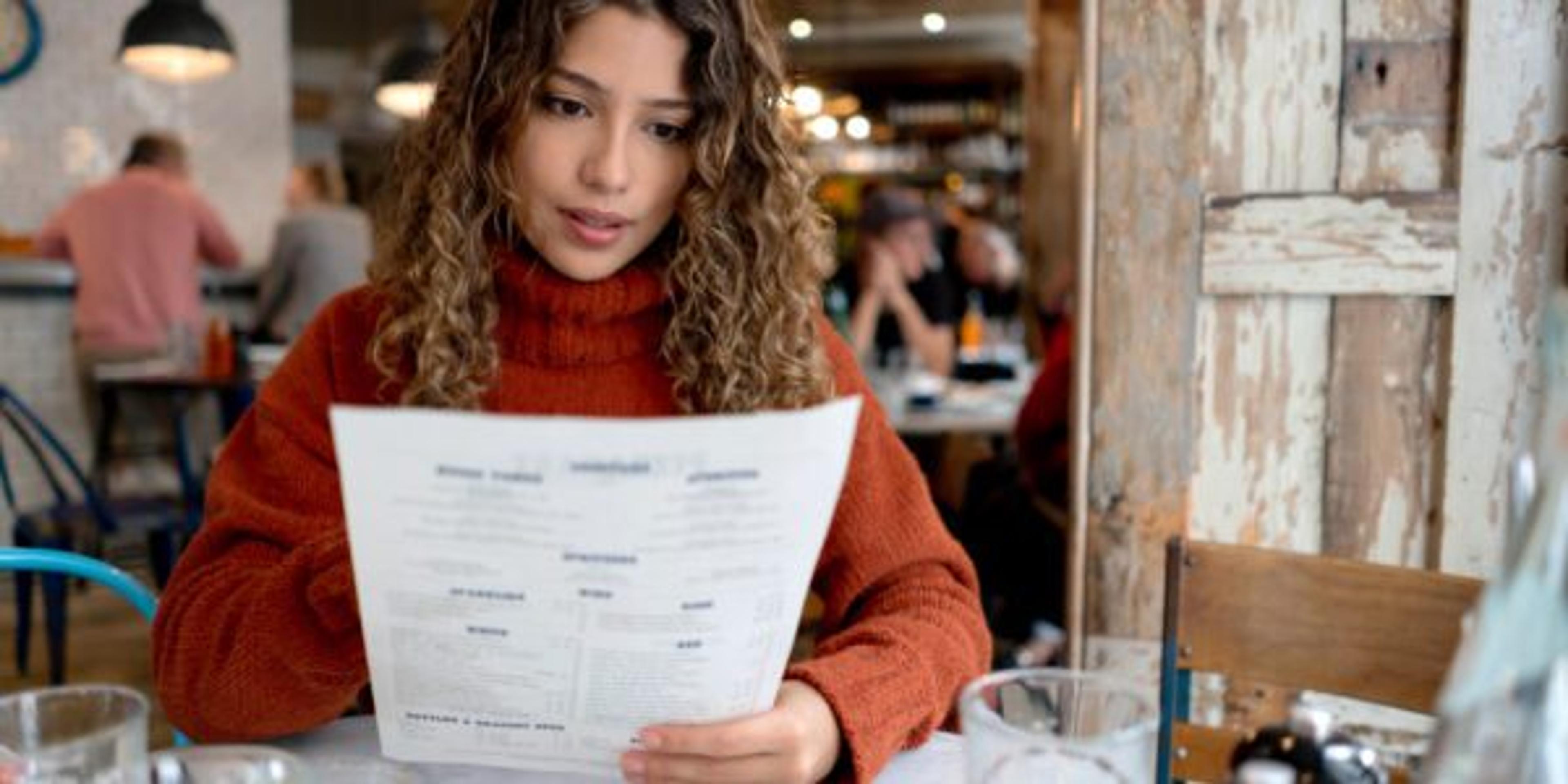 Woman at a restaurant reading the menu