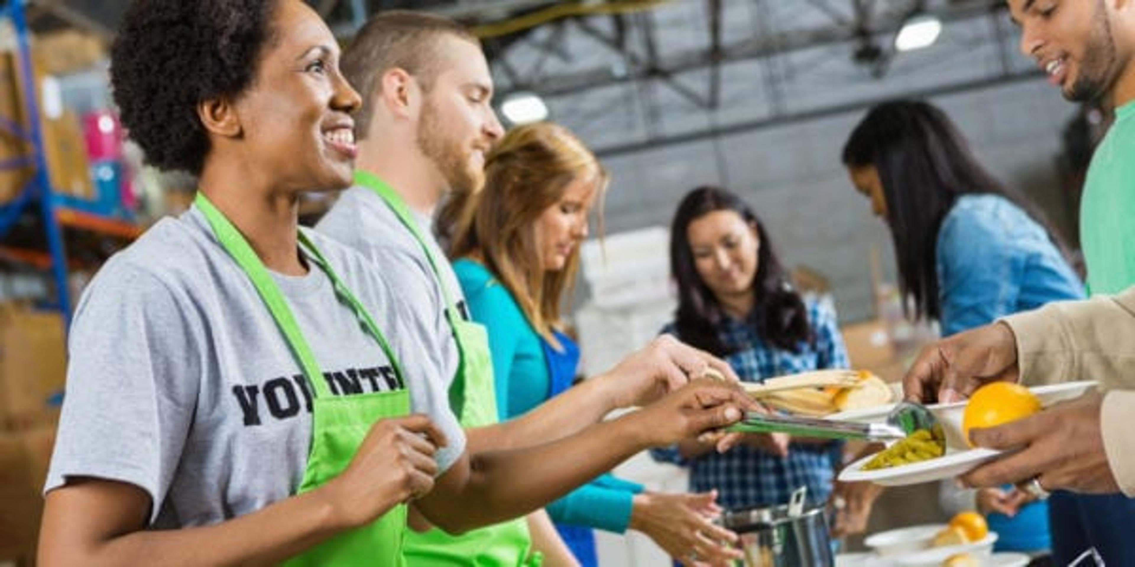 Volunteers serving healthy hot meal at a soup kitchen.