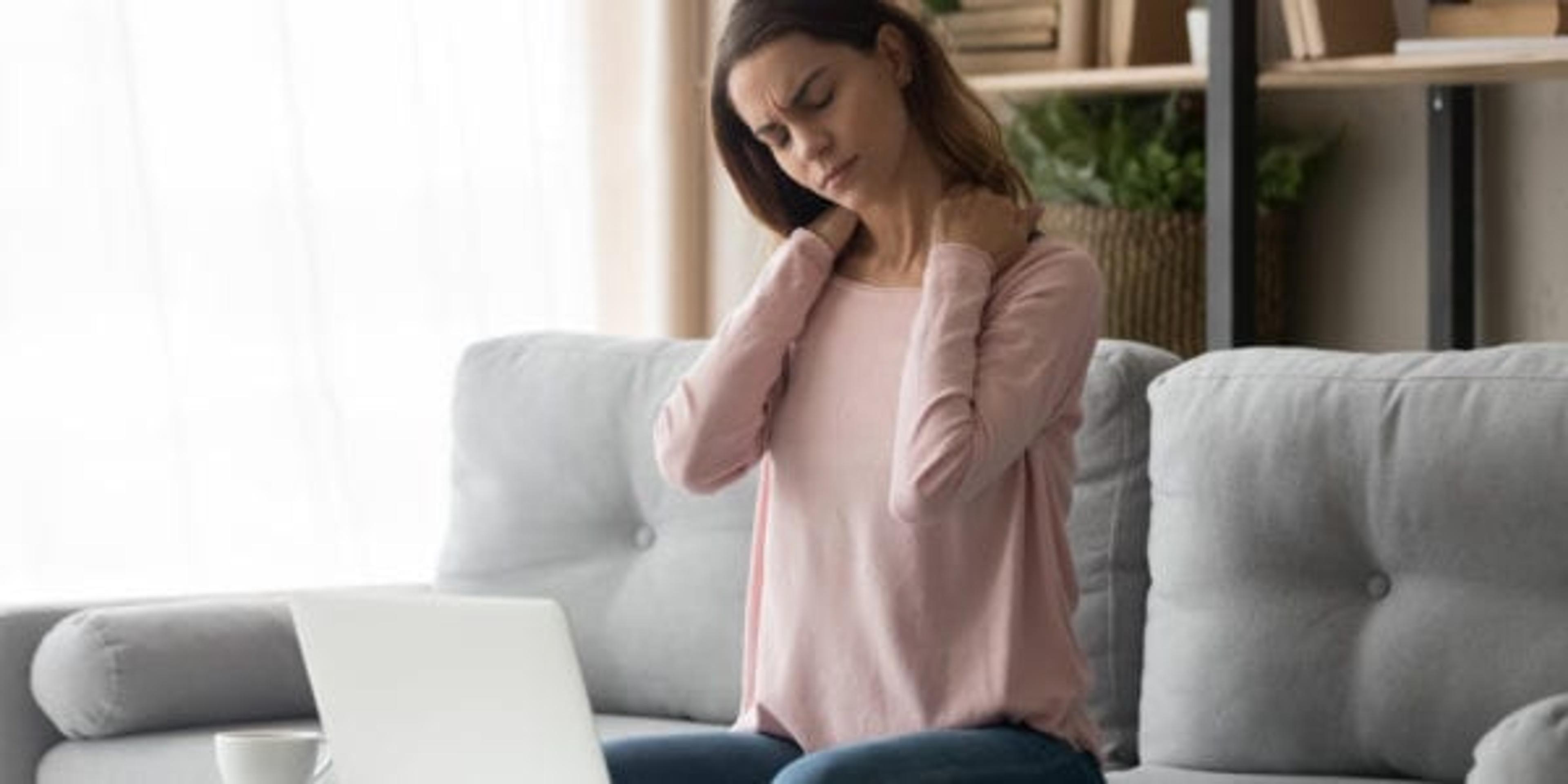 Tired woman feeling neck pain after computer work at home