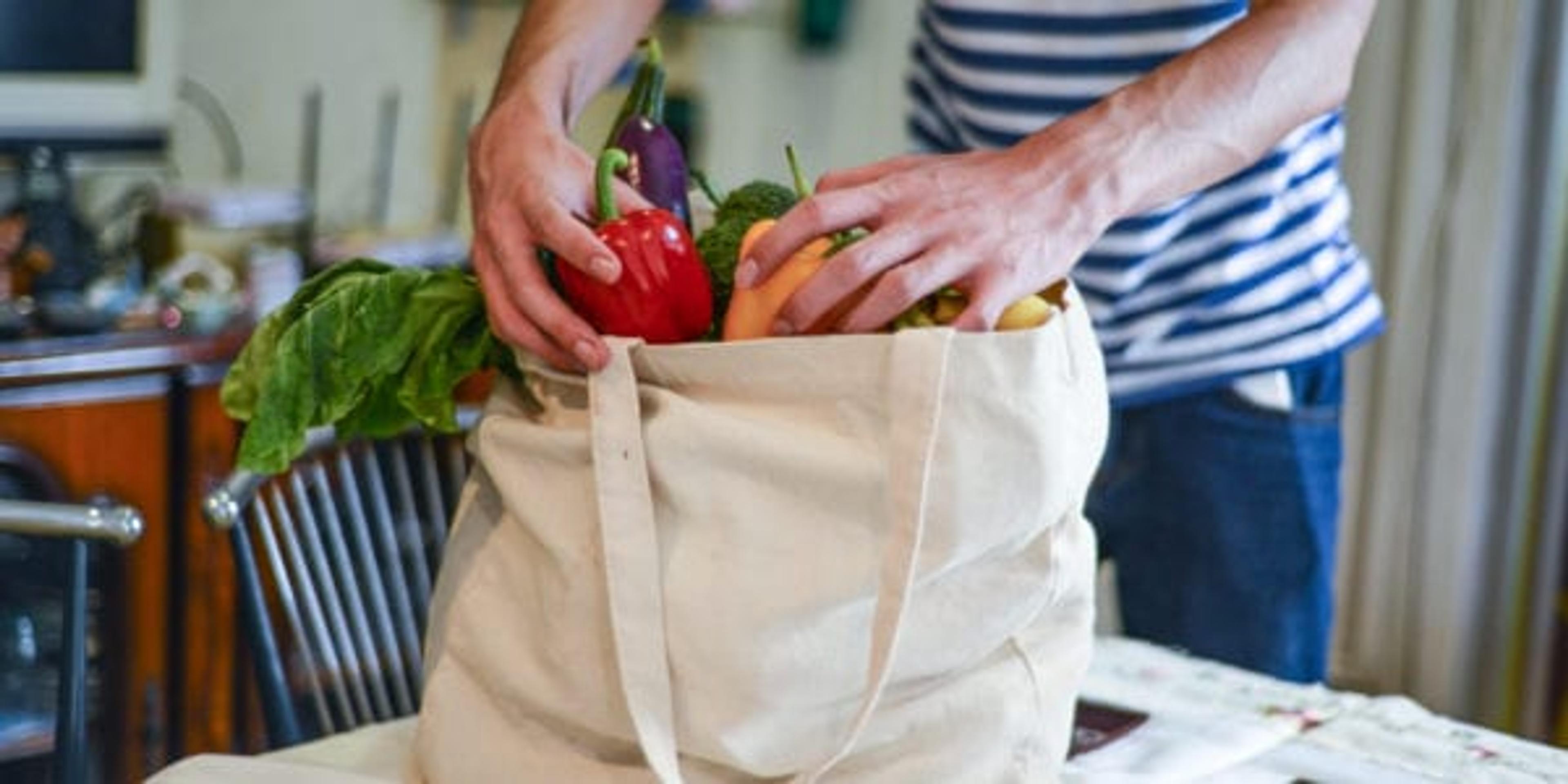 Asian man unpacking groceries at kitchen island