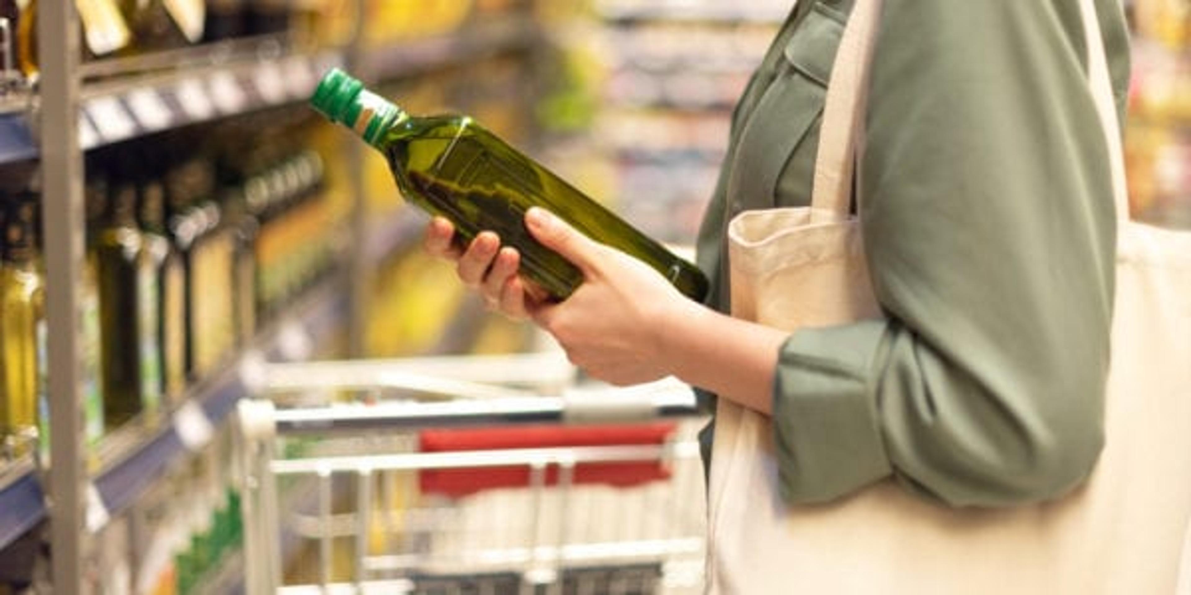 Girl choosing bottle of oil in grocery section of supermarket. Copy space. Healthy diet concept. Sustainable lifestyle.