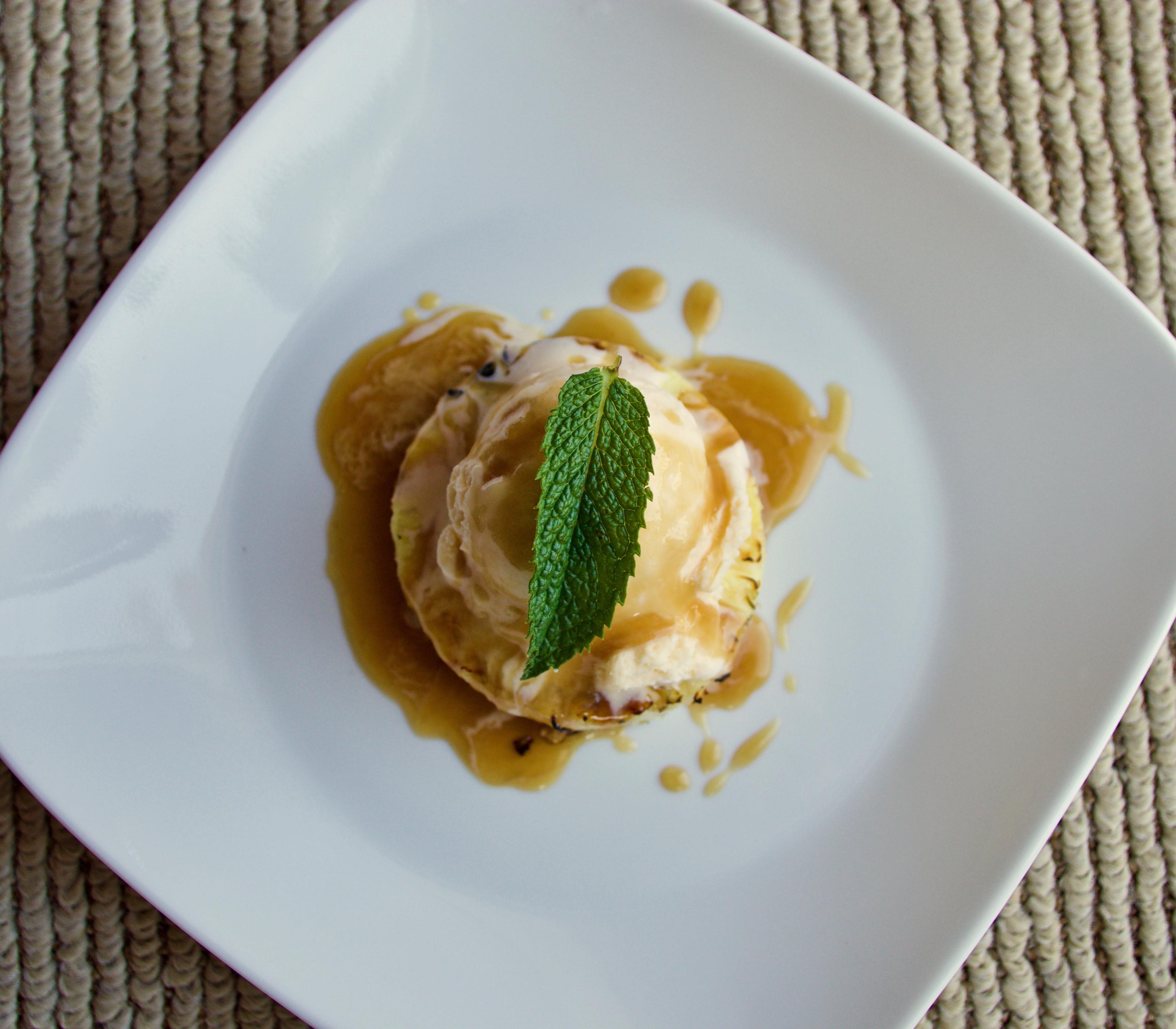 Grilled pineapple with vanilla frozen yogurt on a plate.