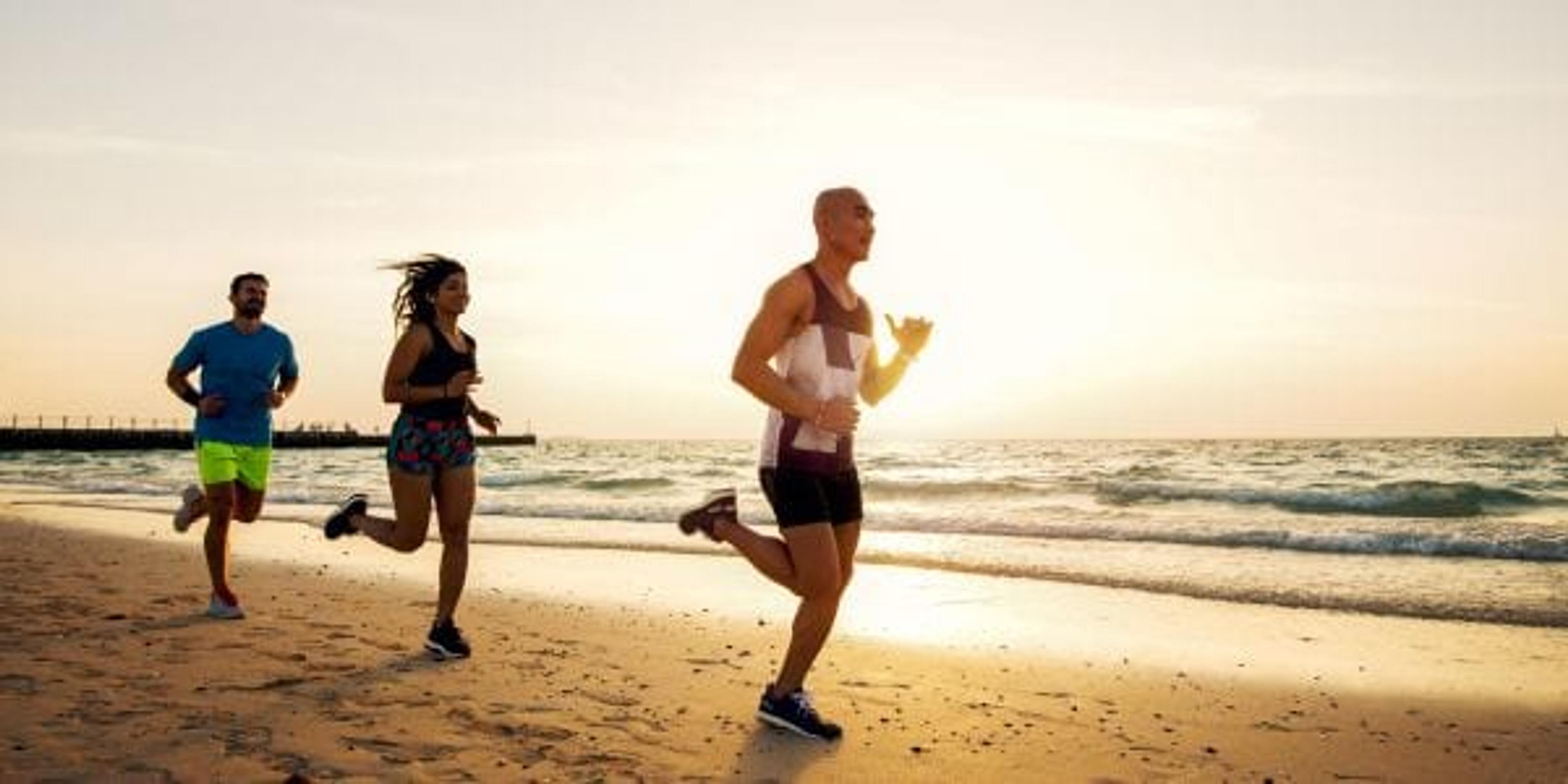 Group of sportive people running on the beach.
