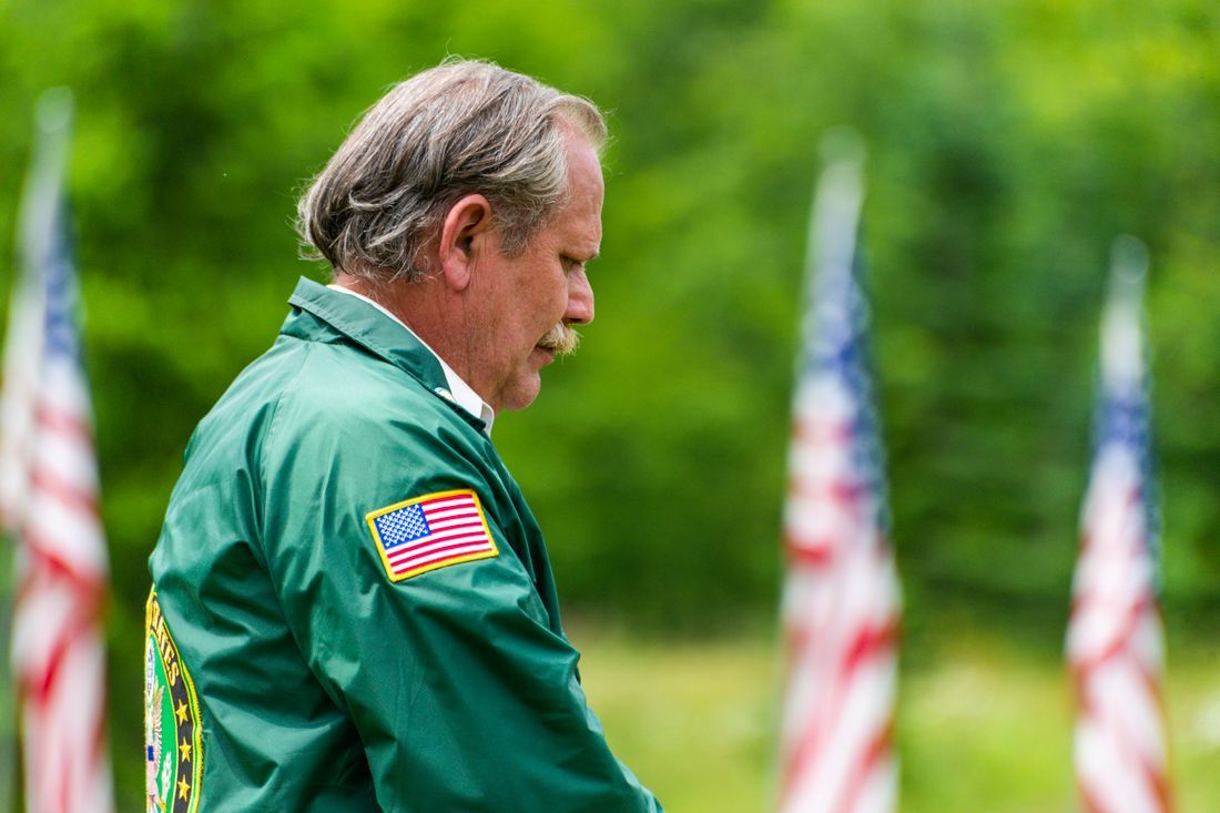A veteran bowing his head in remembrance among the flags