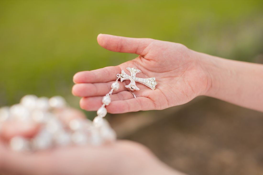 Hands holding a rosary with a cross