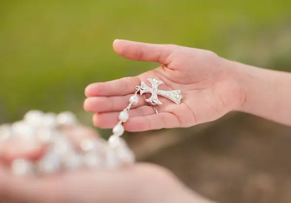 Hands holding a rosary with a cross